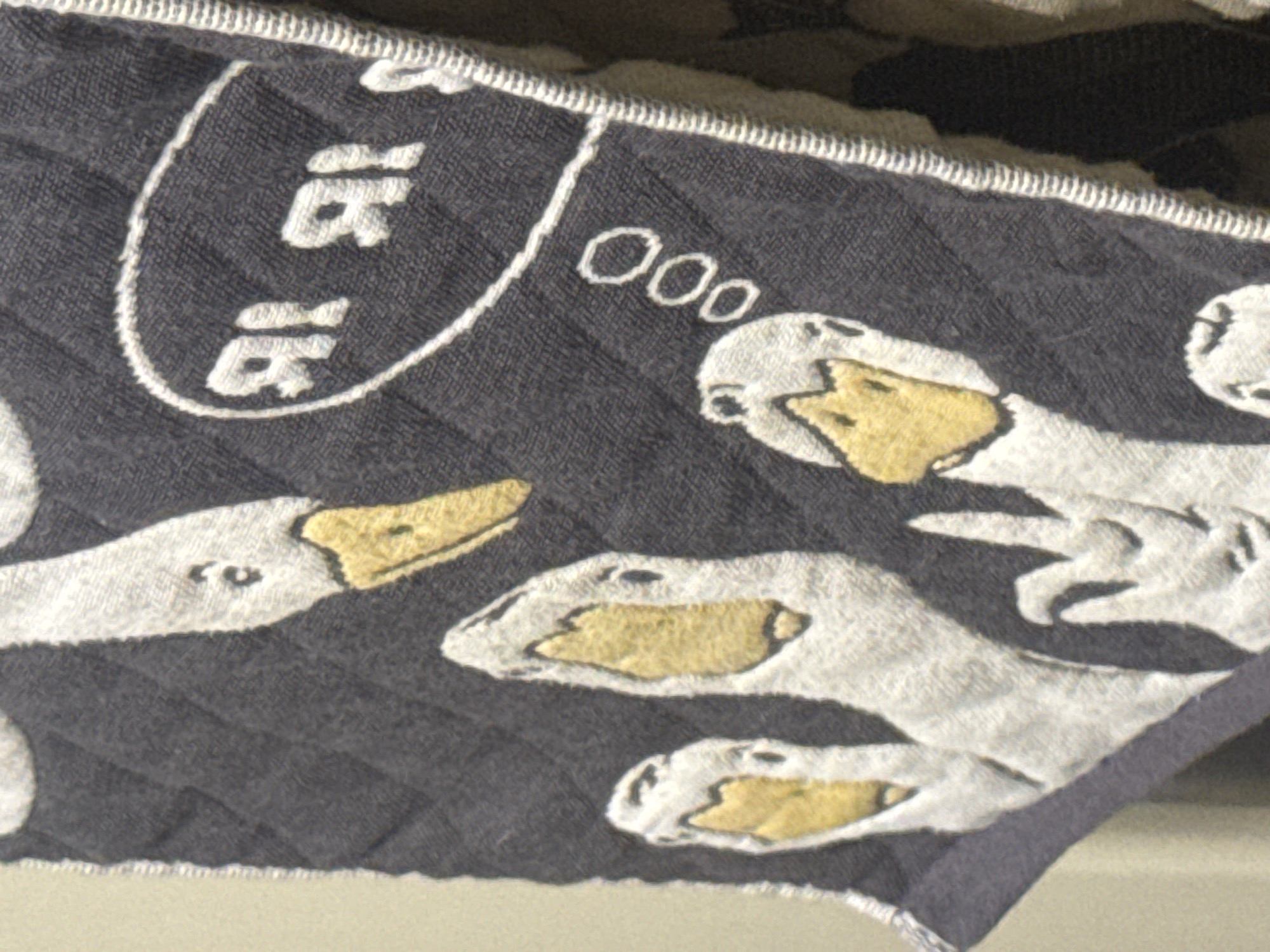 This is a close-up, angled shot of a quilted, dark gray fabric with a pattern of white geese. The geese have yellow beaks and black eyes. Some of the geese are depicted as talking or thinking, indicated by white oval speech bubbles with "ooo" inside. The fabric has a quilted pattern of diagonal lines. The image does not provide any information that would indicate a location in Moscow, Russia, or any details about people, actions, or interactions.