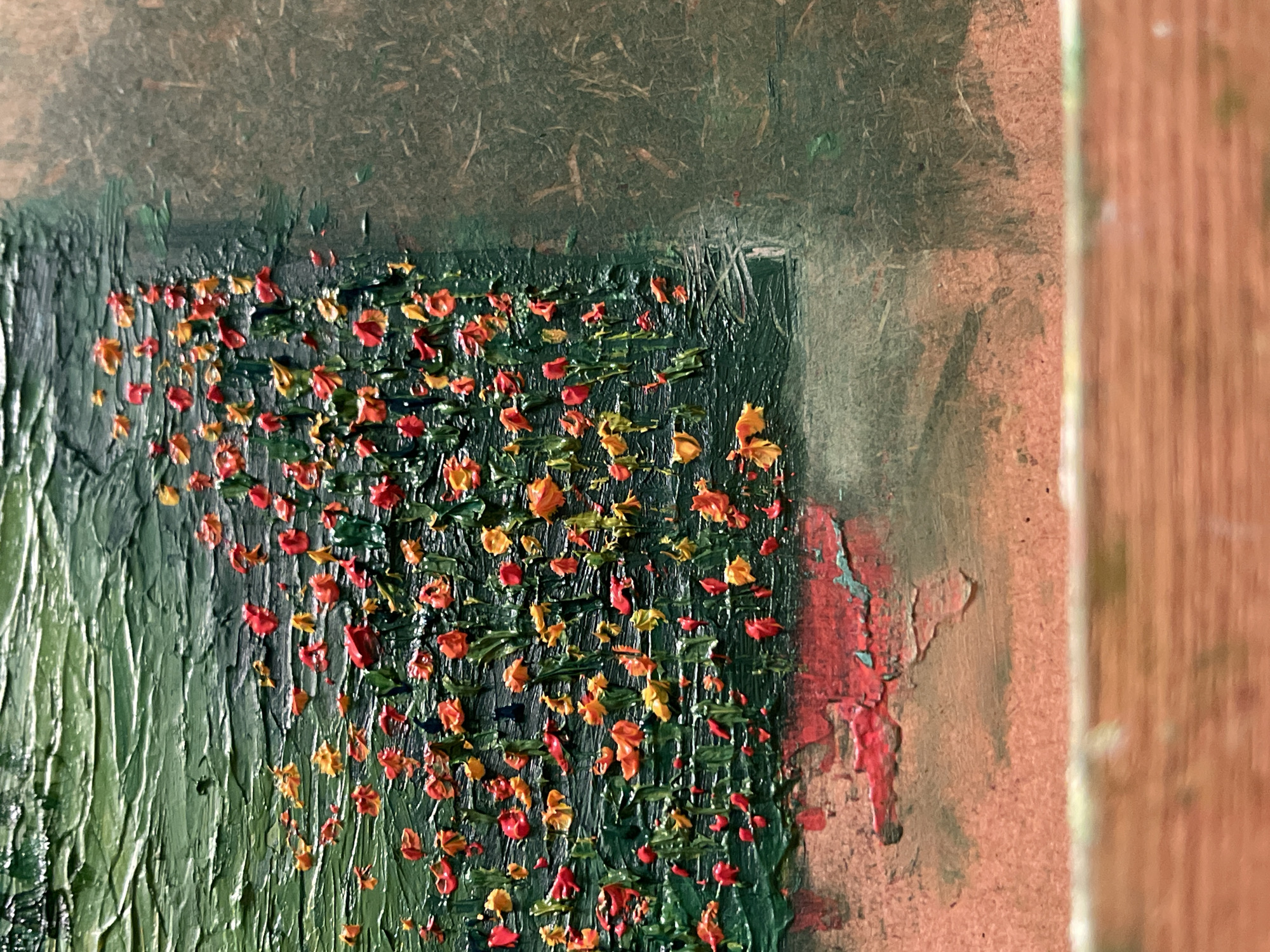 A close-up, abstract oil painting, primarily green with orange and red accents. Thick, vertical strokes of green paint dominate the left side, suggesting foliage. Scattered throughout are small, raised dabs of orange, red, and yellow paint, resembling tiny flowers or leaves. A faint, darker green square is visible, indicating a possible painted border. The artwork appears to be unfinished; the background is a coarse, unfinished board. To the right, there are spots of red and orange paint, and the edge of a wooden frame. The image does not contain enough information to place the scene at Maidstone, United Kingdom.