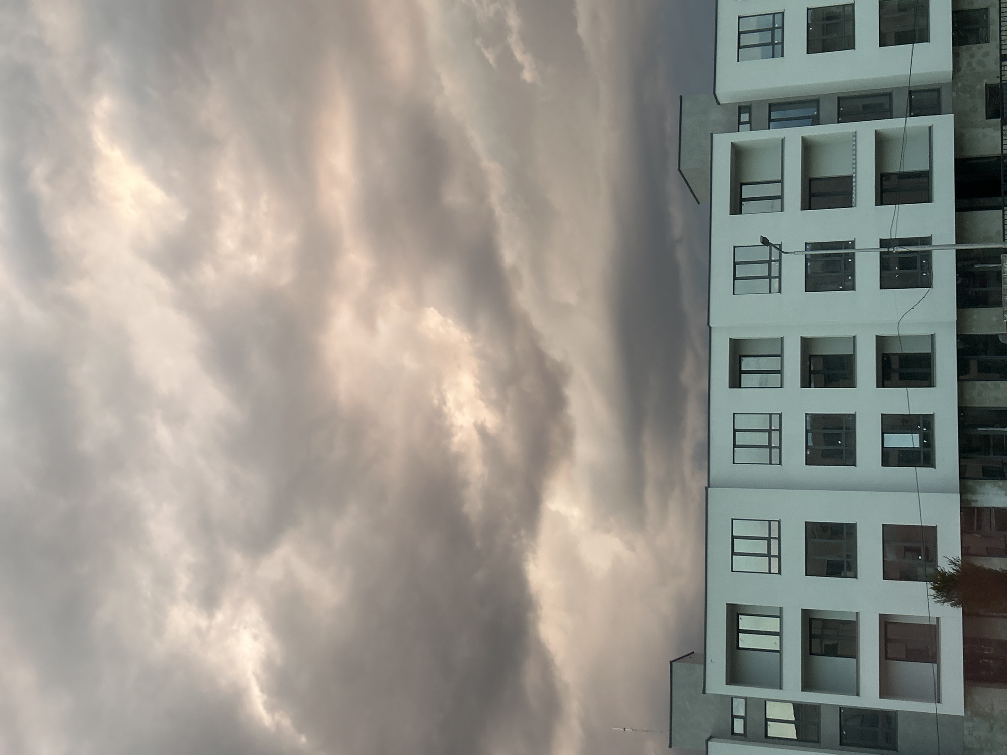 The image shows a cloudy sky and a white building in Plovdiv, Bulgaria. The building has multiple floors with windows.