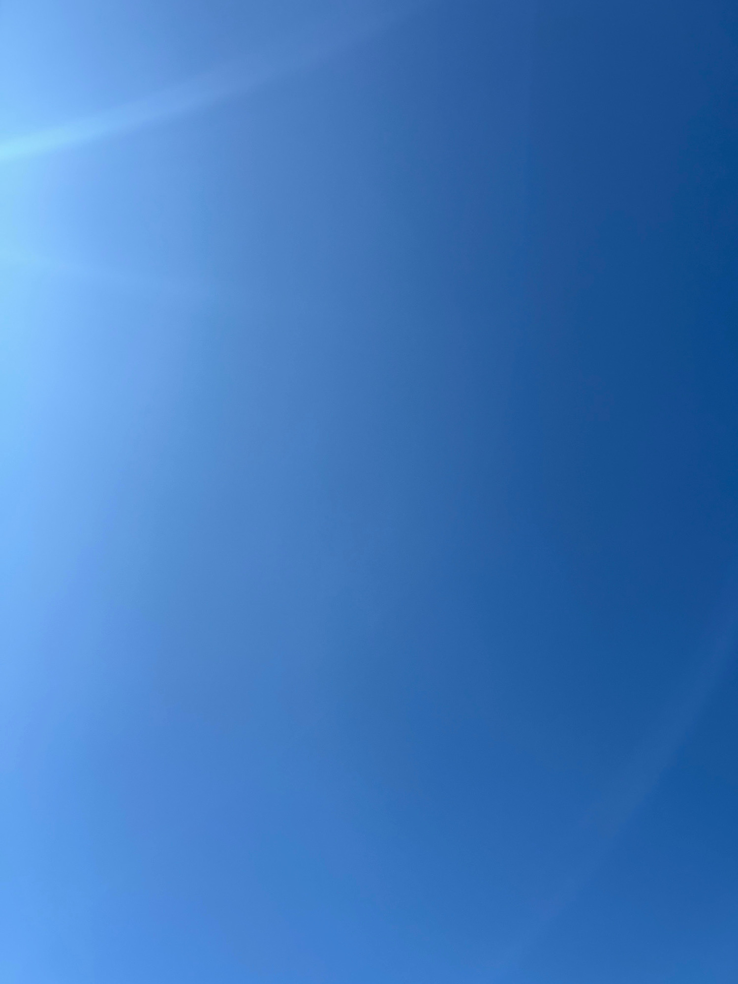 The image is a wide shot of a clear blue sky with subtle lens flare in the upper left corner. There are no objects, people, or discernible features in the sky that would indicate a specific location in Astana, Kazakhstan. The image is devoid of any architectural elements, landmarks, or ground features typically associated with a cityscape.