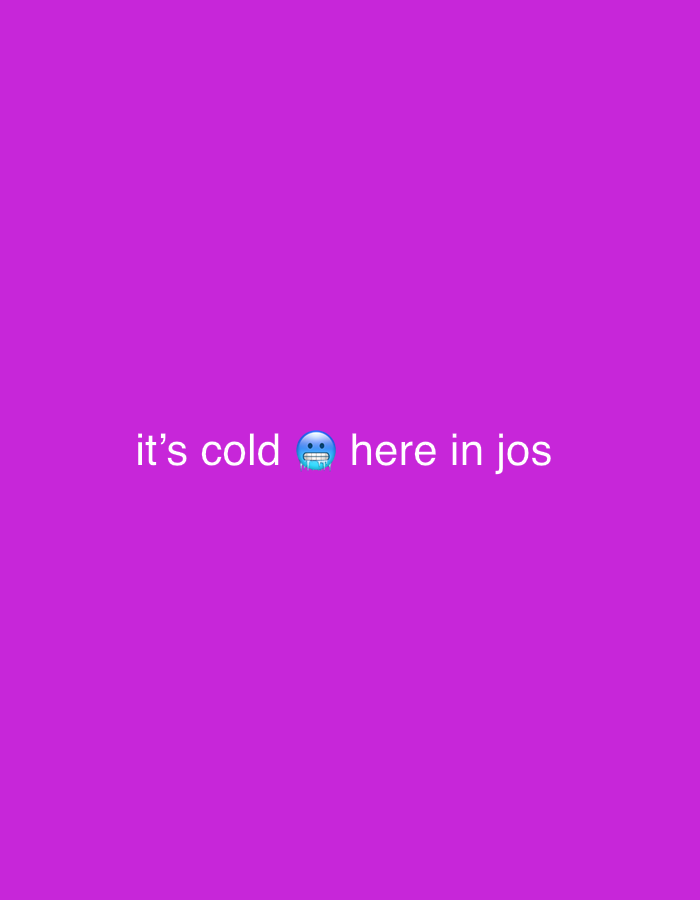 The image is a flat, solid purple background with white text overlaid. The text reads: "it's cold 🥶 here in jos". The emoji depicts a face with a blue tongue and icy breath, indicating coldness. There are no other objects or subjects visible in the image. The location is stated as "jos", which refers to the city of Jos in Plateau State, Nigeria.