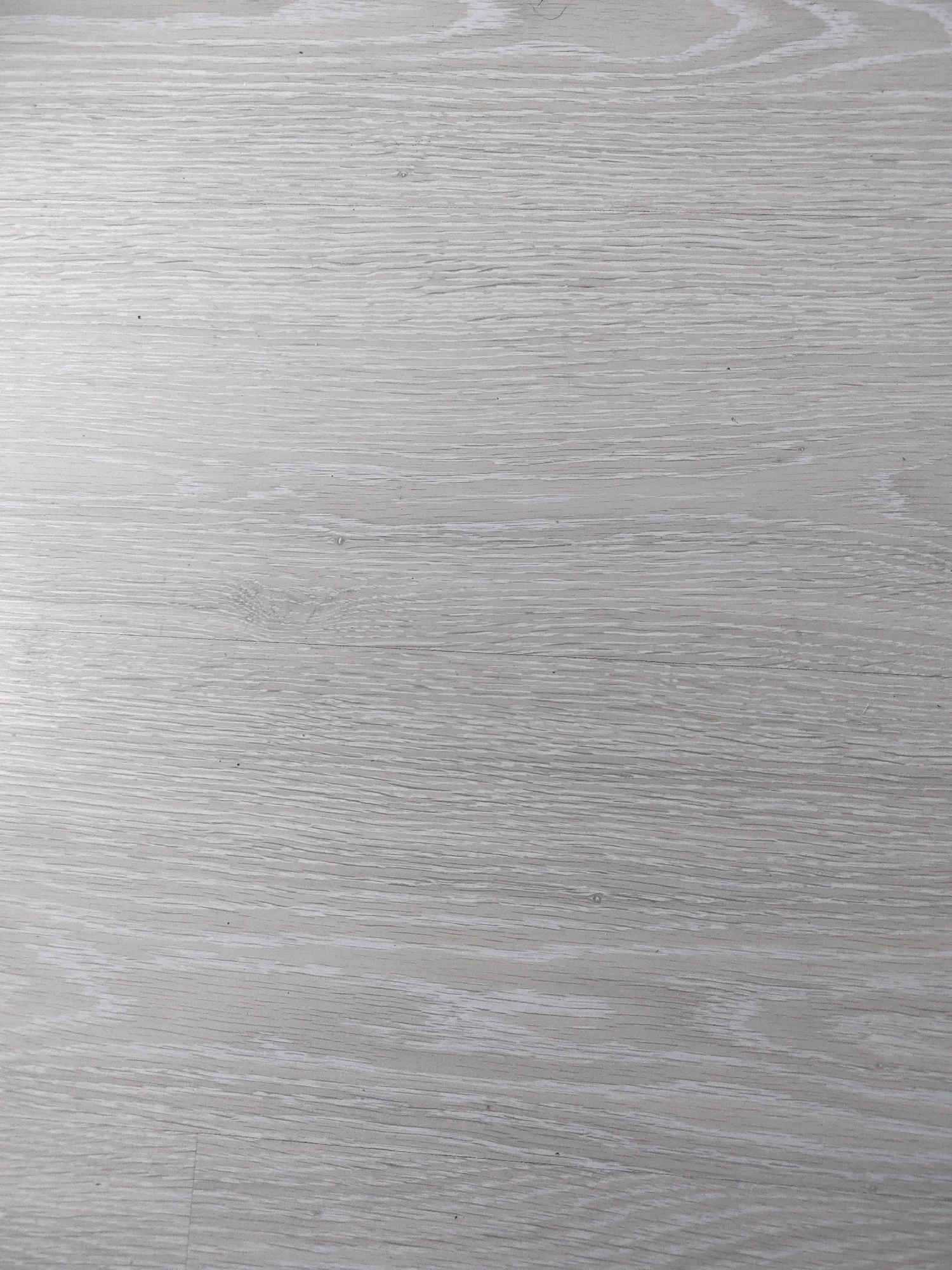 The image is a close-up, overhead shot of a light gray, weathered wooden surface. The wood exhibits a prominent grain pattern with distinct, parallel lines and some subtle variations in tone, suggesting an aged or distressed finish. There are no people, objects, or discernible actions depicted in the image. The texture of the wood is the sole focus. The location in Porto Recanati, Italy, is not visually ascertainable from the image itself.