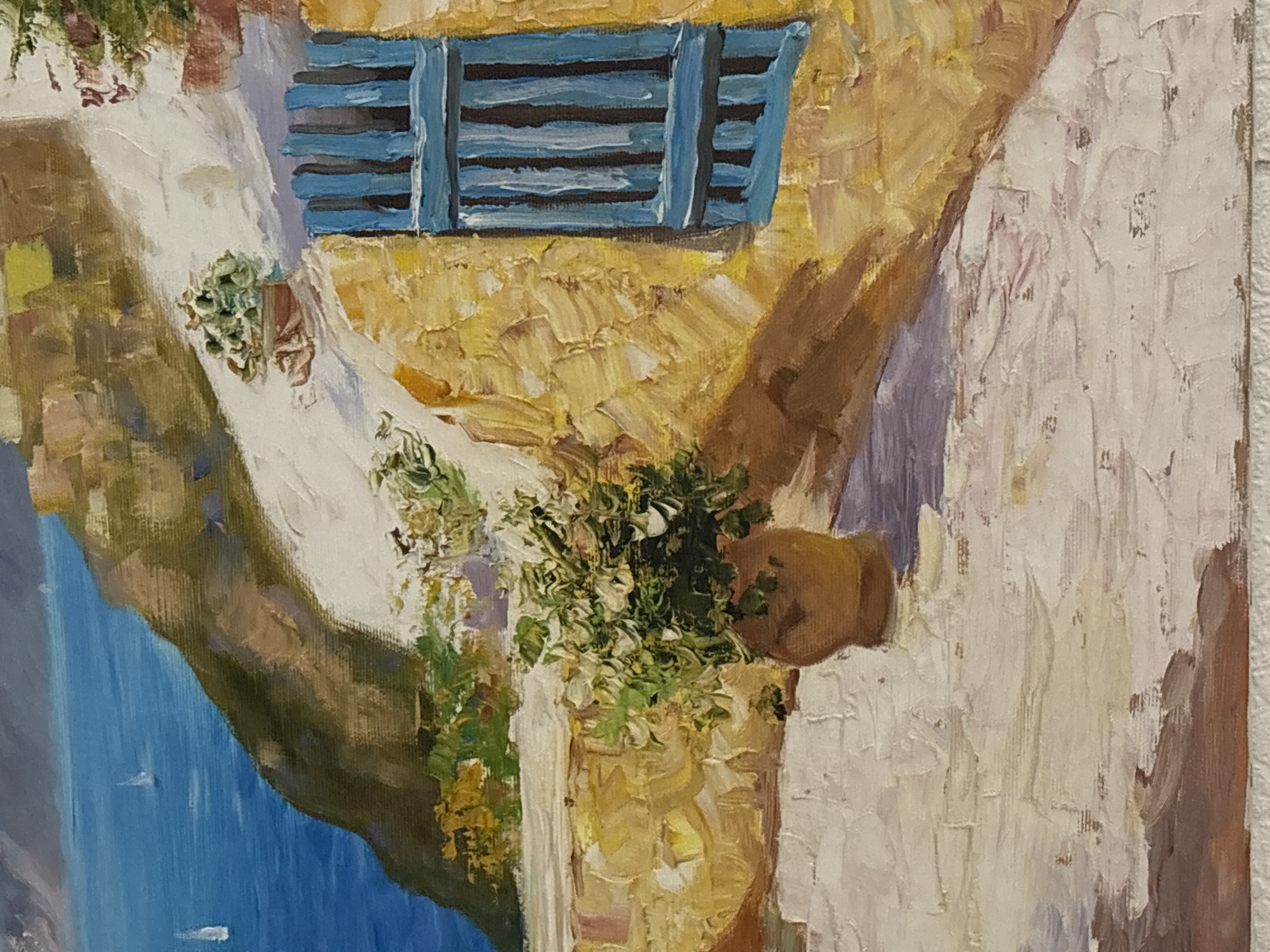 This is a close-up, impressionistic oil painting of a Mediterranean coastal scene, likely depicting a building with a blue shuttered window. The style is characterized by thick, visible brushstrokes, giving a textured and vibrant appearance. The color palette features warm yellows and oranges for the building, contrasting with the deep blue of the sea and the blue shutters. Green foliage in terracotta pots adds touches of life to the scene. In the background, the blue sea extends to the horizon, with distant sailboats visible. The foreground is a textured ground, possibly a stone pathway or courtyard, with shadows cast from the building. The painting does not depict any specific location in the city of Kyiv, Ukraine, but rather a generalized picturesque coastal landscape.