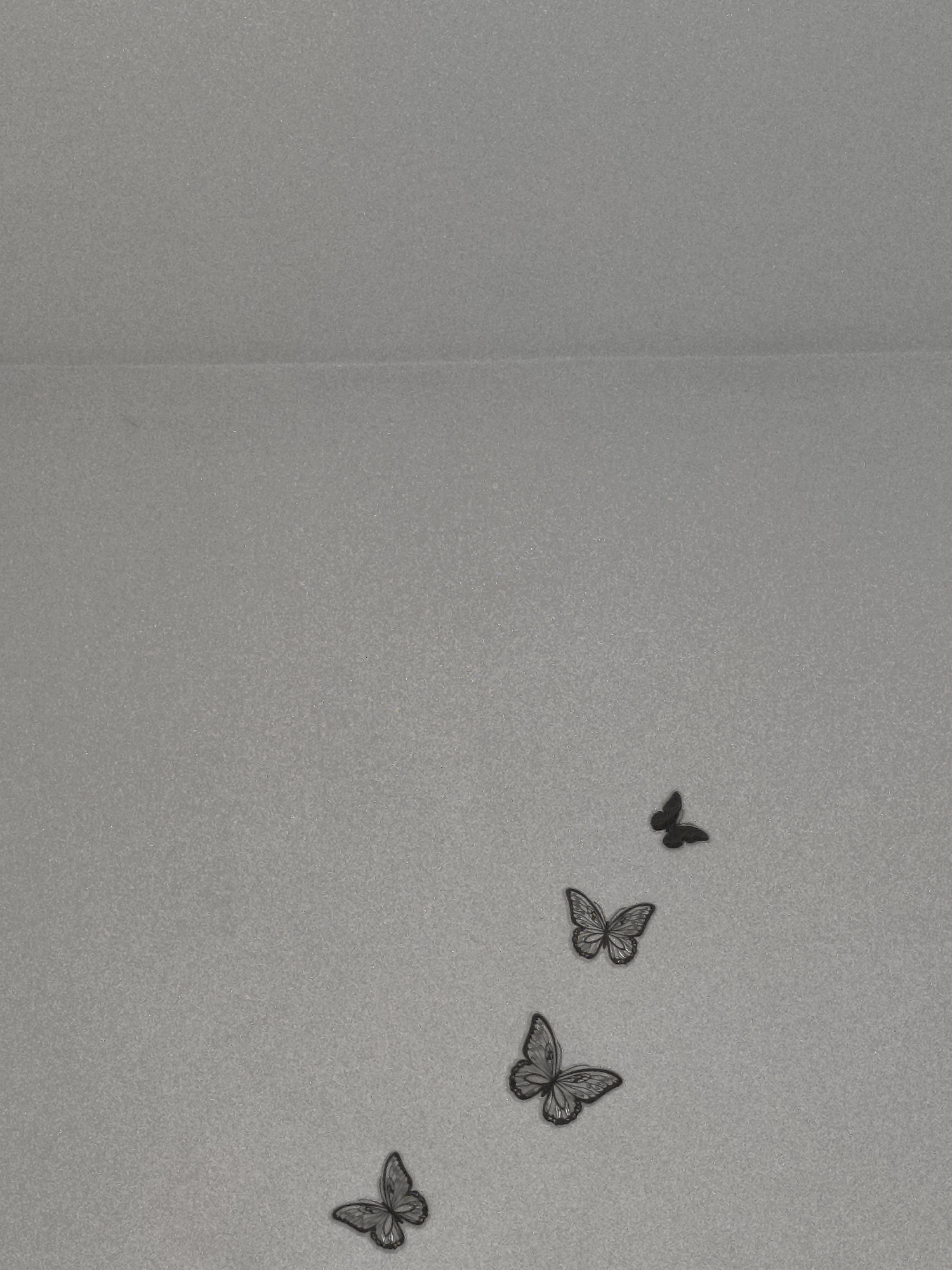 The image depicts four dark-colored butterfly decorations affixed to a textured, light gray surface. The butterflies are arranged in a diagonal, ascending pattern, with the smallest butterfly at the top and the largest at the bottom. The location is not discernable from the visual information provided.