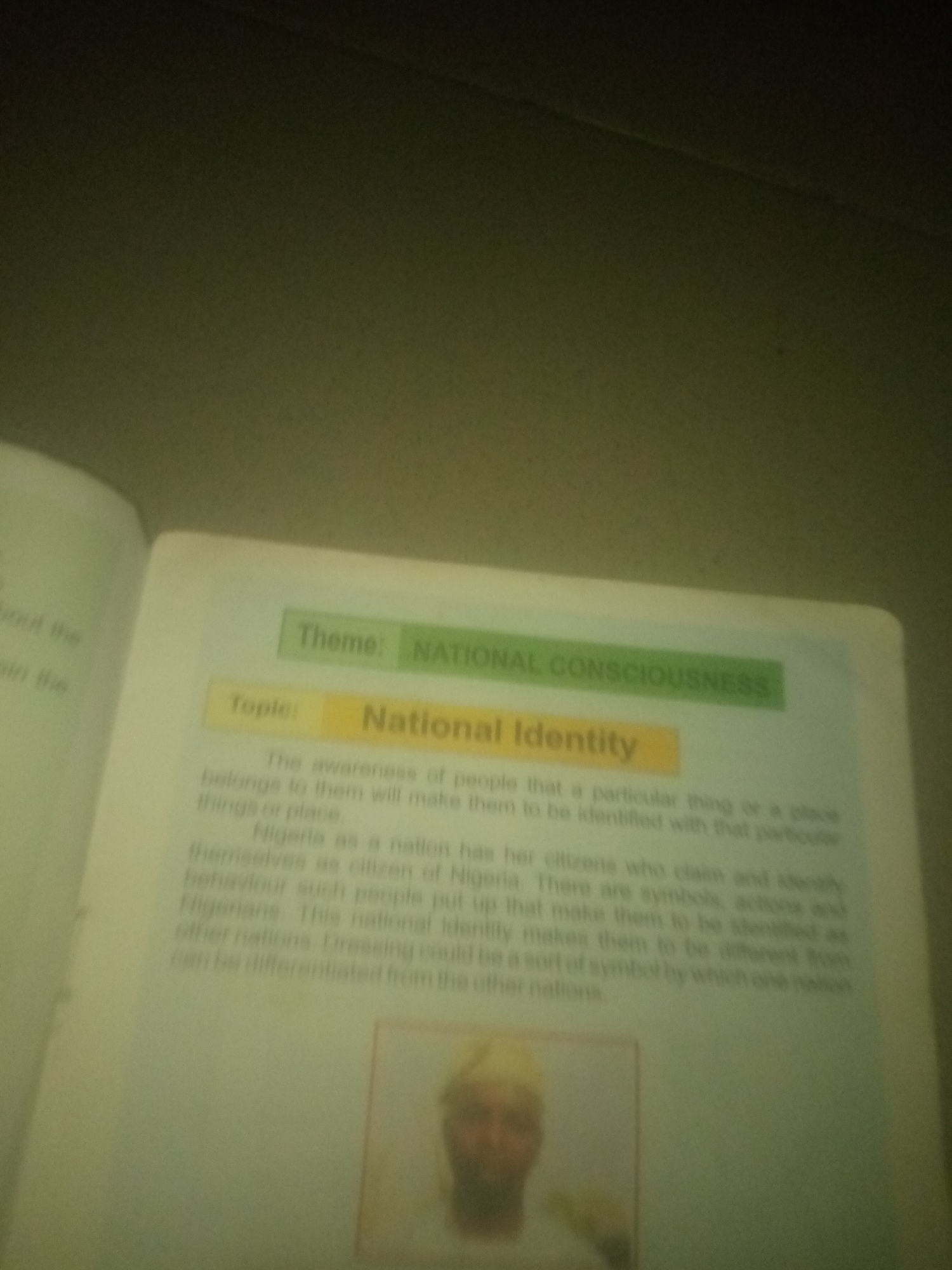 The image shows an open book with text and a photograph. The text discusses "National Consciousness" and "National Identity," specifically mentioning Nigeria and its citizens. The photograph appears to be of a person. The image is taken in Jauro Yinu, Nigeria.