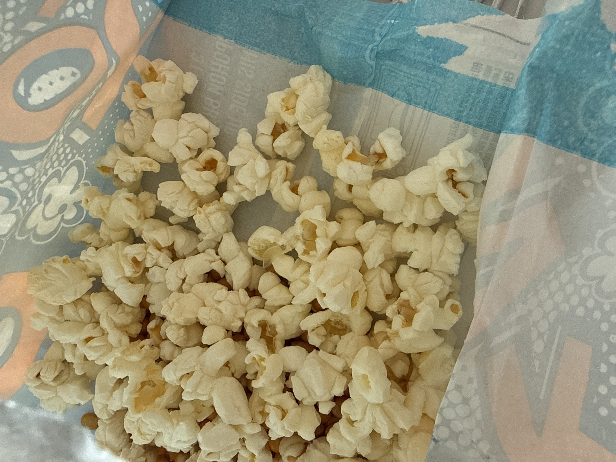 The image shows a bag of popcorn. The bag has a blue and white design with floral and geometric patterns. The popcorn is light yellow and fills a portion of the bag. The location, Vorontsovo, Russia, cannot be determined from the visual information provided.
