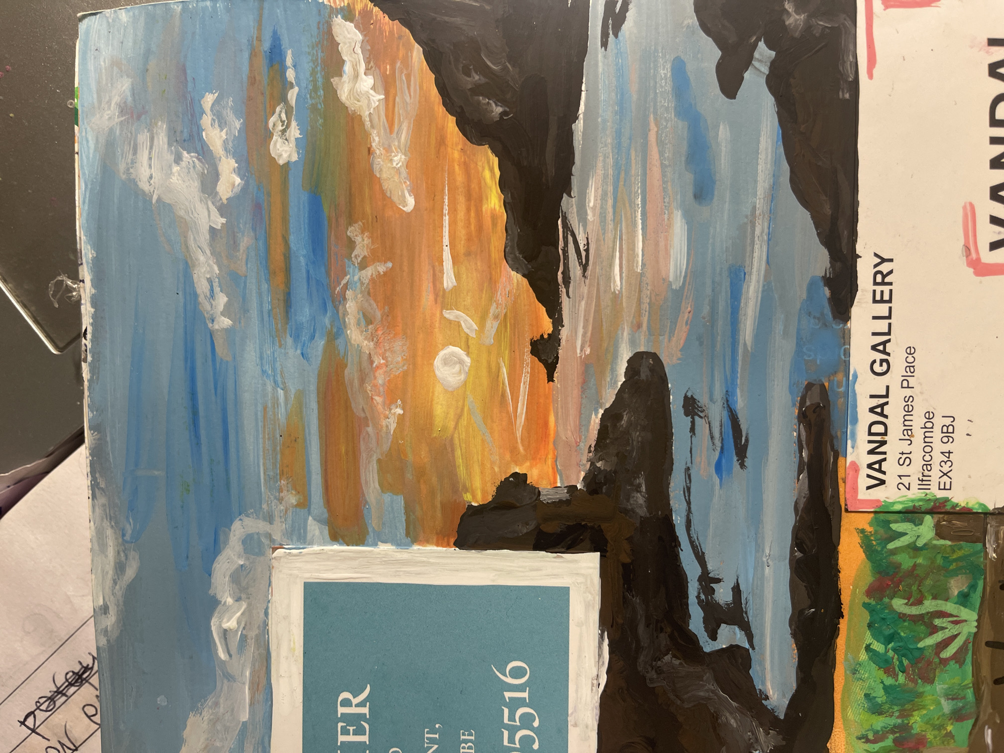 The image displays a photograph of an expressive, abstract painting, likely executed with acrylics or gouache, presenting a dynamic landscape or seascape. The artwork is characterized by bold, visible brushstrokes and a vibrant palette of blues, oranges, yellows, and blacks, with white and green accents. Large, dark, amorphous shapes frame or divide areas of lighter color. One prominent section features a bright orange and yellow background with a white circular shape and streaky white marks, suggesting a sunset or sunrise. Other significant portions are in various shades of blue, punctuated by white brushstrokes that could represent clouds or reflections on water. A small area of green at the bottom hints at foliage or land.
The painting rests on a surface, with several pieces of paper or card partially visible around it. A key textual element, rotated on the right side, clearly identifies "VANDAL GALLERY" at "21 St James Place, Ilfracombe, EX34 9BJ." This provides a specific location cue for the gallery associated with the painting. Additionally, a blue card with a white border is partially visible at the bottom, displaying text including "ER" and a number "5516." Other fragmented text, such as "pore," "NT," and "BE," appears on other background scraps. The photograph presents an artistic piece within a casual setting, providing direct geographic information pointing to Ilfracombe in the United Kingdom.