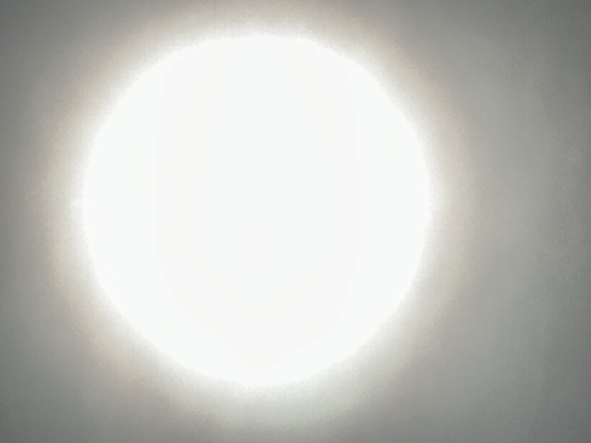 The image shows a bright, circular light source, likely the sun or a strong artificial light, dominating the center of the frame. The light is surrounded by a diffuse, greyish area, possibly representing the sky or a hazy atmosphere. The details are obscured by the intensity of the light and the lack of clear textures in the surrounding area. There are no discernible objects, people, or identifiable environmental features. Without additional context or visual cues, determining the exact location, especially in Nizhny Novgorod, Russia, is impossible.