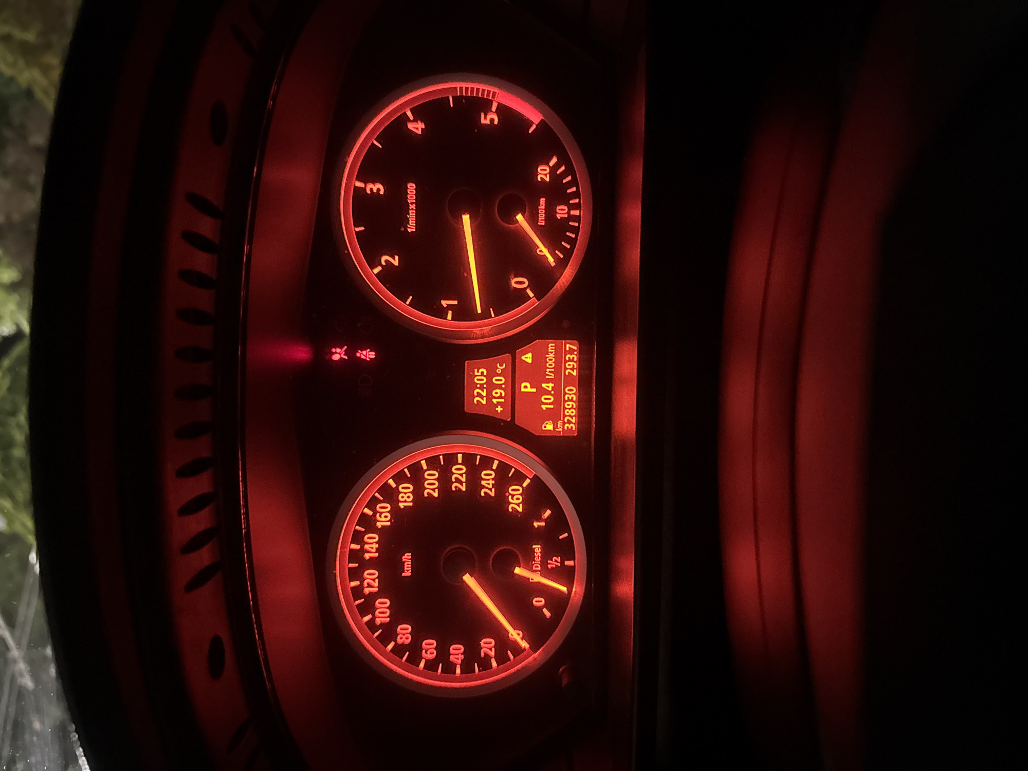 This image shows the dashboard of a car. The tachometer reads around 2,000 RPM. The speedometer displays approximately 110 km/h. The fuel gauge is reading about half full, and the information display shows a fuel consumption of 10.4 l/100km with an outside temperature of 19 degrees Celsius. The gear selection is in Park (P). The odometer reads 328930 km. The time displayed is 22:05. There is a warning light illuminated indicating an airbag or seatbelt issue. Given the presence of "km/h" on the speedometer and the language visible in the image, it is reasonable to say this vehicle is operating within Europe, but there is no specific evidence in the image to connect it to Stara Zagora, Bulgaria.