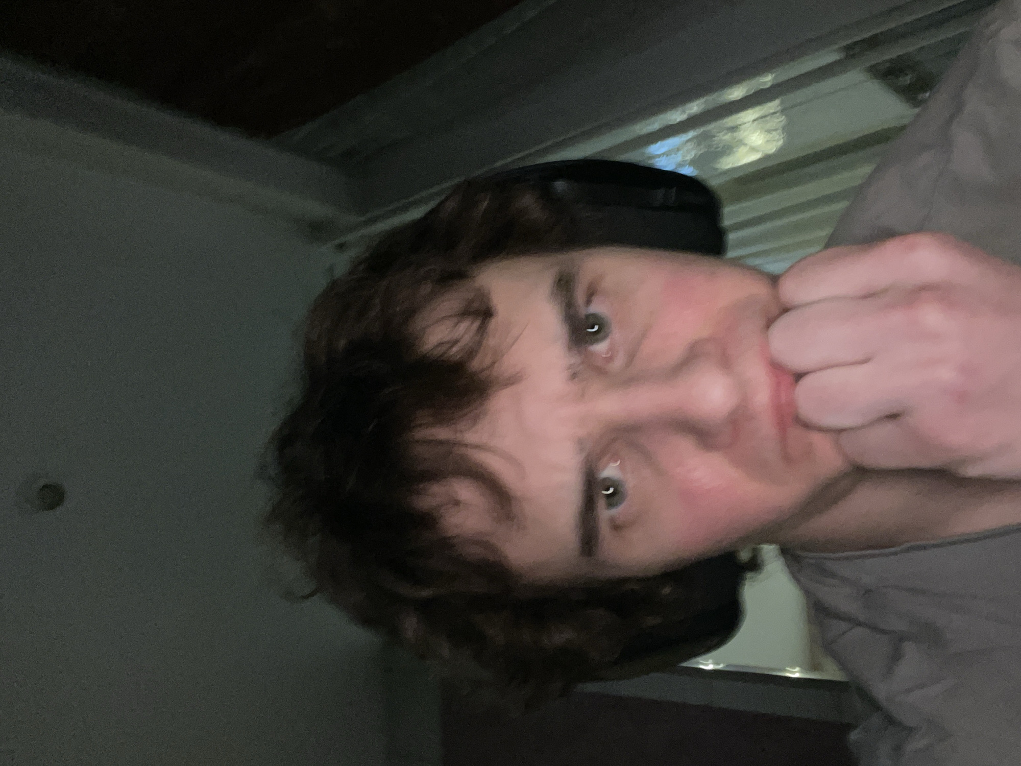 A man with brown hair and headphones is holding his fist to his mouth, looking directly at the camera. The scene is indoors. It is not possible to determine if this image was taken in Krasnoyarsk, Russia, without further information.