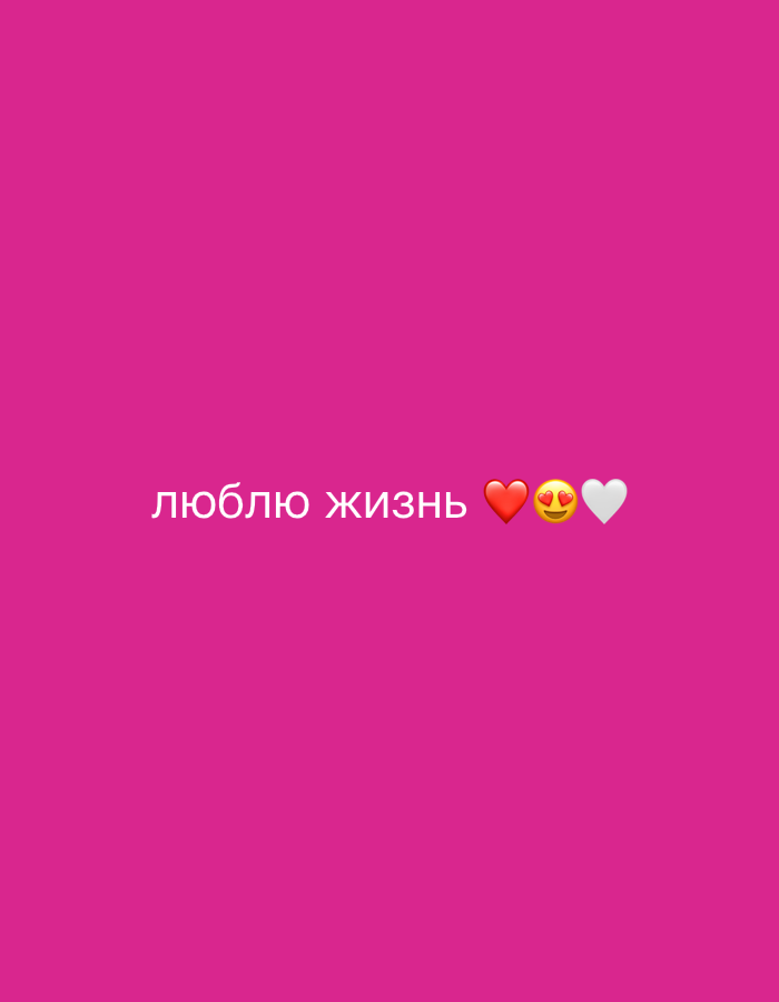 The image is a photograph of text and emojis against a bright pink background. The text, in white, reads "люблю жизнь" which translates to "I love life". To the right of the text are three emojis: a red heart, a face with hearts for eyes, and a white heart. The image does not contain any information or visual cues that would allow for a description of a location in Yuzhno-Sakhalinsk, Russia, nor does it depict any people, objects, actions, or interactions.