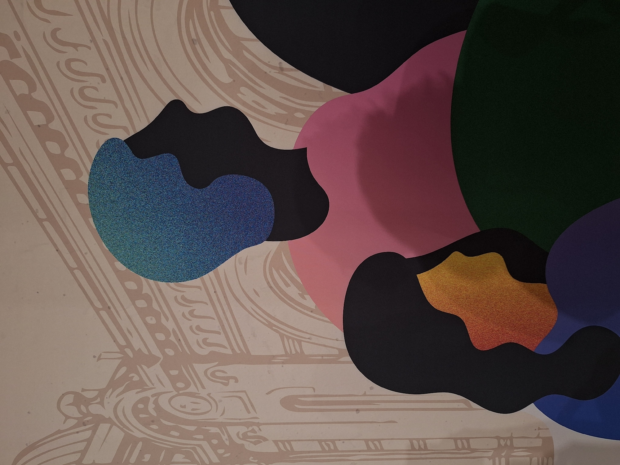 The image displays an abstract artwork composed of overlapping, organically shaped forms against a decorative patterned background. Large, smooth shapes in solid black, dark pink/magenta, dark green, and dark blue/purple occupy the upper and right portions of the frame, creating a sense of depth and layering. Amongst these, two distinct shapes stand out with a textured, glittery appearance: one in vibrant blue/teal and another in shimmering gold/orange.
The background is a light beige or tan, featuring intricate line-art patterns in a lighter brown or sepia tone. These patterns are highly detailed and flowing, reminiscent of classical architectural ornamentation, decorative scrollwork, or stylized natural motifs like waves or clouds. The abstract shapes are positioned over this patterned backdrop, partially obscuring it.
The artwork combines bold, contemporary abstract elements with traditional decorative designs. There are no people or discernible activities taking place. The overall impression is static and artistic, focusing on color, form, and texture contrasts. No text is visible.