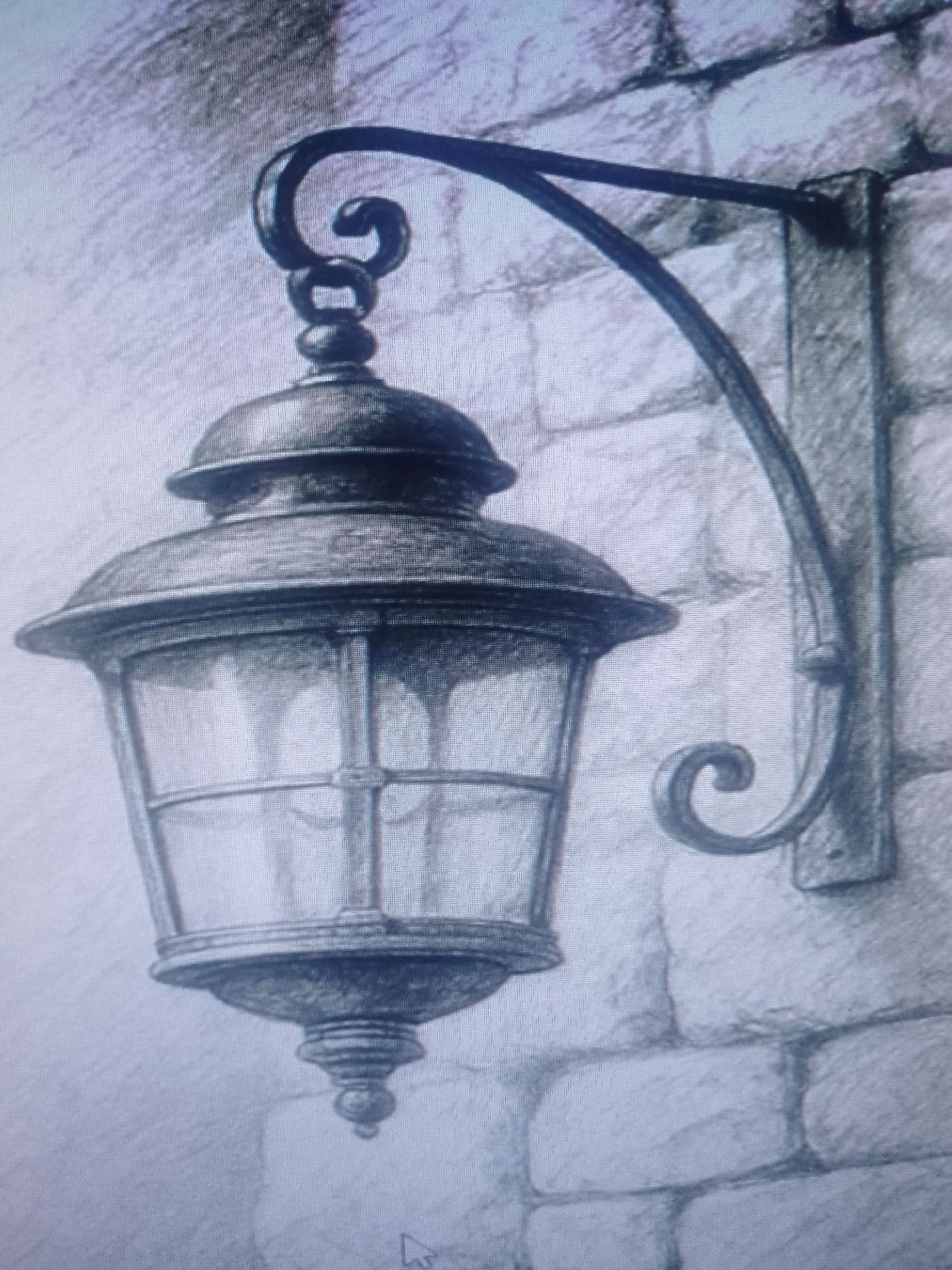 A detailed charcoal-style drawing depicts an ornate, wrought-iron lantern attached to a brick wall. The lantern hangs from a curved arm, with a decorative scroll at both the top and where it meets the wall. The lantern itself has a multi-tiered top, glass panels, and a decorative finial at the bottom. The brick wall is rendered with shading to indicate texture and individual brick shapes. The location is unspecified.