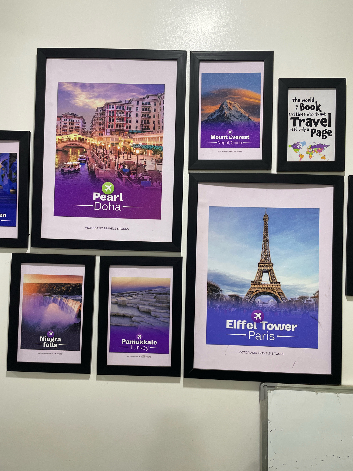 The image displays a wall adorned with framed travel posters. The posters feature various destinations: "Pearl - Doha", "Mount Everest - Nepal/China", "Niagara Falls - Turkey", and "Eiffel Tower - Paris". There is also a smaller framed poster with the text "The world is Book and those who do not Travel read only a Page" and a colorful world map. The overall arrangement suggests a decorative display of travel inspiration. The location is identified as Abuja, Nigeria.