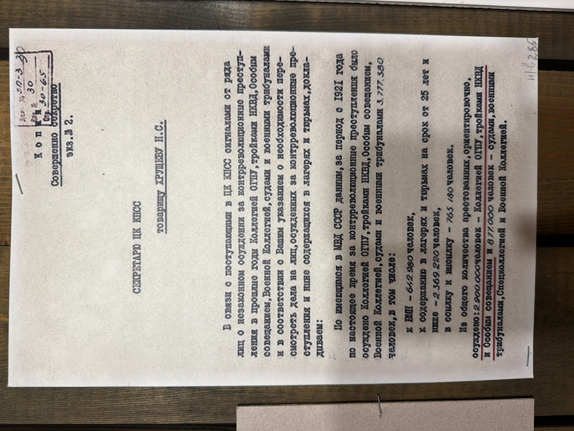 The image shows a document with Russian text. The document appears to be a formal letter or report, with a stamp at the top right corner and a handwritten number at the bottom right. The text discusses criminal convictions and the legal system in the Soviet Union. There is no information in the image that relates to the city of Ust'-Pyzas, Russia. The document itself is the sole subject of the image, presented against a wooden background.