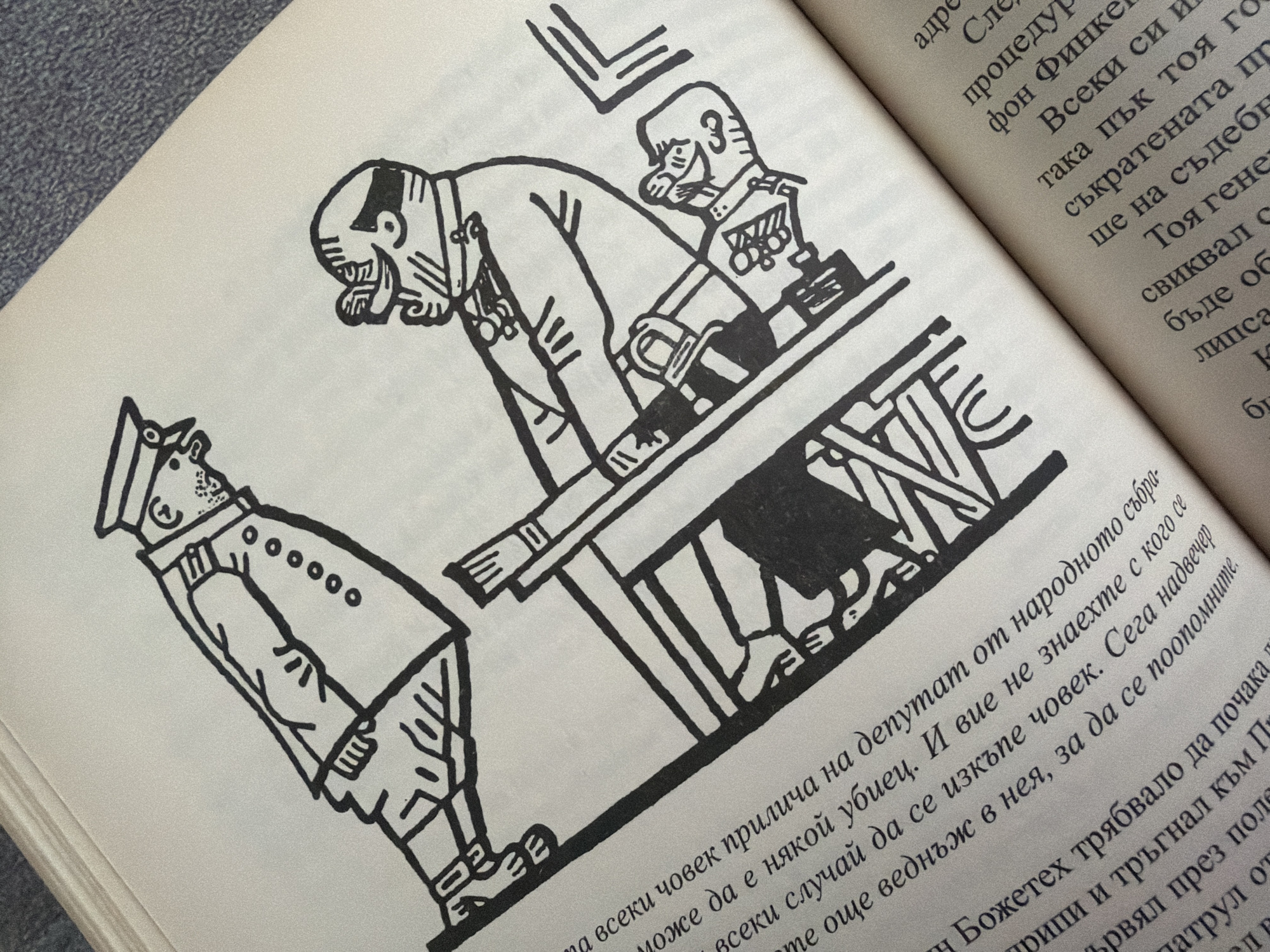 The image depicts a black and white illustration from a book, showing two figures and a table. The upper figure is standing and wearing a cap and a uniform with multiple buttons. The lower figure is seated at a table, wearing a helmet-like head covering and a suit. A third, smaller figure is visible, partially obscured, also at the table. The illustration style is simple and cartoonish. The text in the image is in Bulgarian, suggesting the book's origin or content. There is no information about the city of Pazardzhik, Bulgaria, or any specific location within it.
