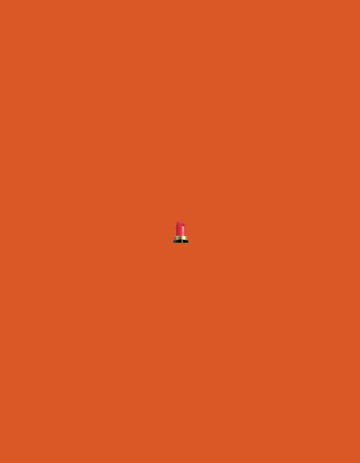 The scene, located in the city of Santa Ana, Venezuela, presents a minimalistic composition. A single lipstick is centrally positioned against a uniform, solid orange background. The object consists of a cylindrical base, primarily black, featuring a distinct gold band around its upper circumference. From this base, a vibrant reddish-pink cosmetic stick protrudes upwards, ending in a slightly angled, tapered tip. No other subjects, individuals, actions, or environmental elements are discernible within the frame. The setting appears to be an isolated, studio-like environment due to the monochromatic backdrop.
