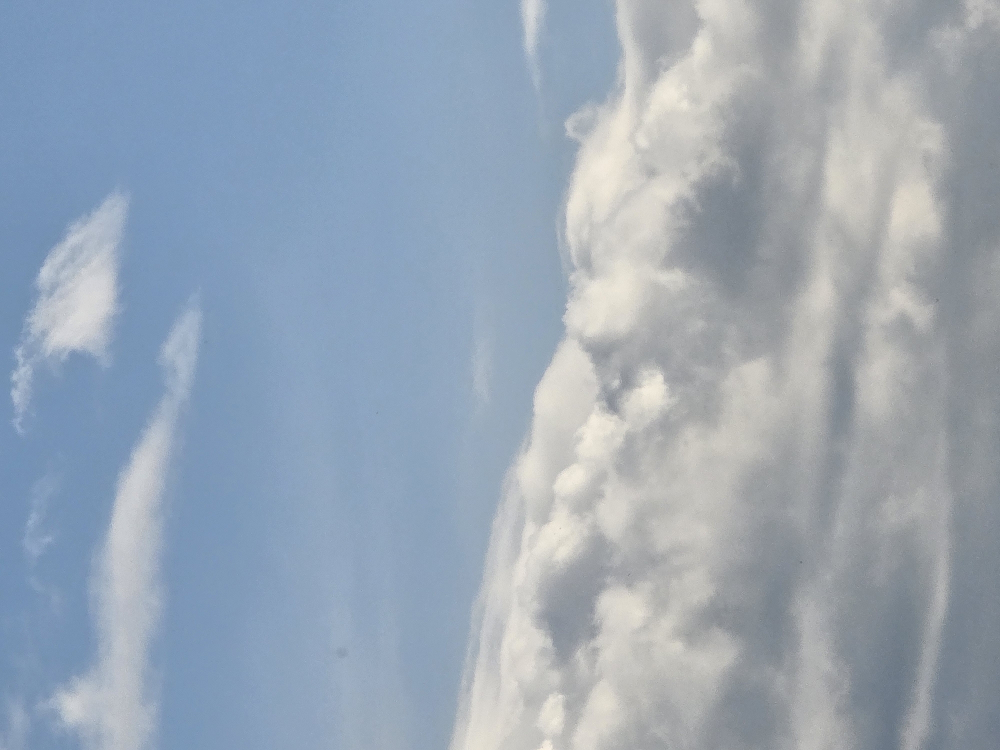 The image shows a blue sky with scattered clouds. Some clouds are thin and wispy, while others are dense and puffy. The overall composition suggests a sunny day with moderate cloud cover. The location of the image is not provided and cannot be determined.