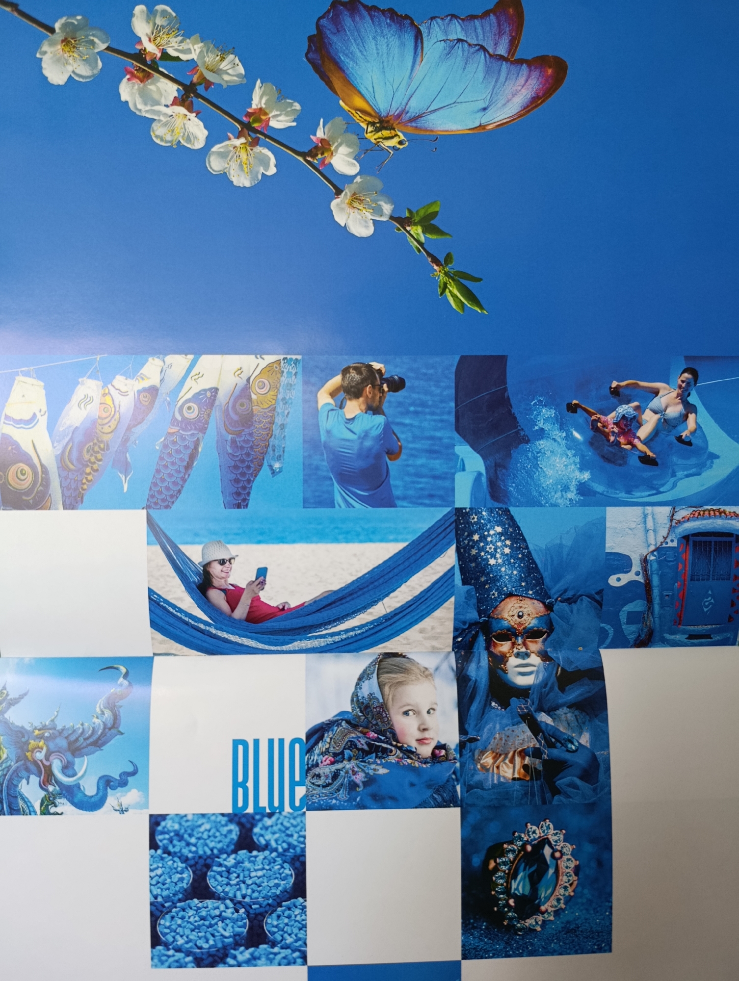 The image is a collage of various blue-themed photographs. At the top, a large blue butterfly with purple and yellow accents is shown against a clear blue sky, with a branch of white blossoms on the left. Below the butterfly, several smaller images are arranged. These include:
* A row of Japanese carp streamers (koinobori) hanging on a line.
* A man in a blue shirt holding a camera, looking away from the viewer.
* A woman in a red dress and a hat lying in a blue hammock on a beach, looking at her phone.
* Two people on a water slide, one in a striped swimsuit and the other in a pink swimsuit, both appearing to be enjoying themselves.
* A blue mask with gold accents and stars on a blue background.
* A young girl wearing a patterned headscarf.
* A detailed image of a blue gemstone ring surrounded by glitter.
* An image of a blue mythical creature with horns and a long trunk.
* The word "BLUE" written in large, blue, block letters.
* A blue door with a red opening on a blue, textured wall.
* Four circular containers filled with small, blue, pellet-like objects, possibly seeds or medication.
The overall impression is a collection of diverse scenes united by the color blue. There is no discernible location in a city specified.