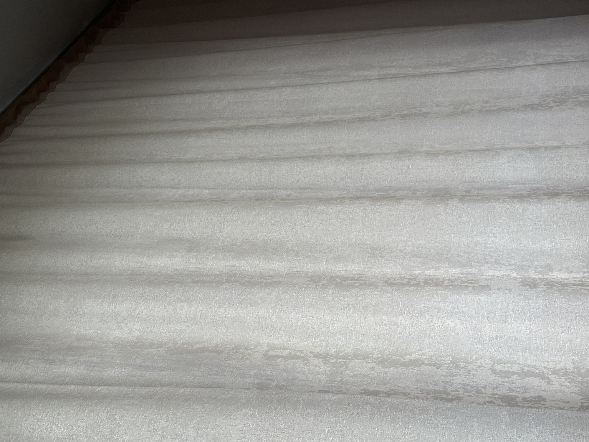The image shows a close-up of a layered, white fabric surface. The fabric has a textured pattern and is folded or layered in a way that creates horizontal lines. The lighting appears to be soft and diffuse. The location and specific context of the image are unknown.