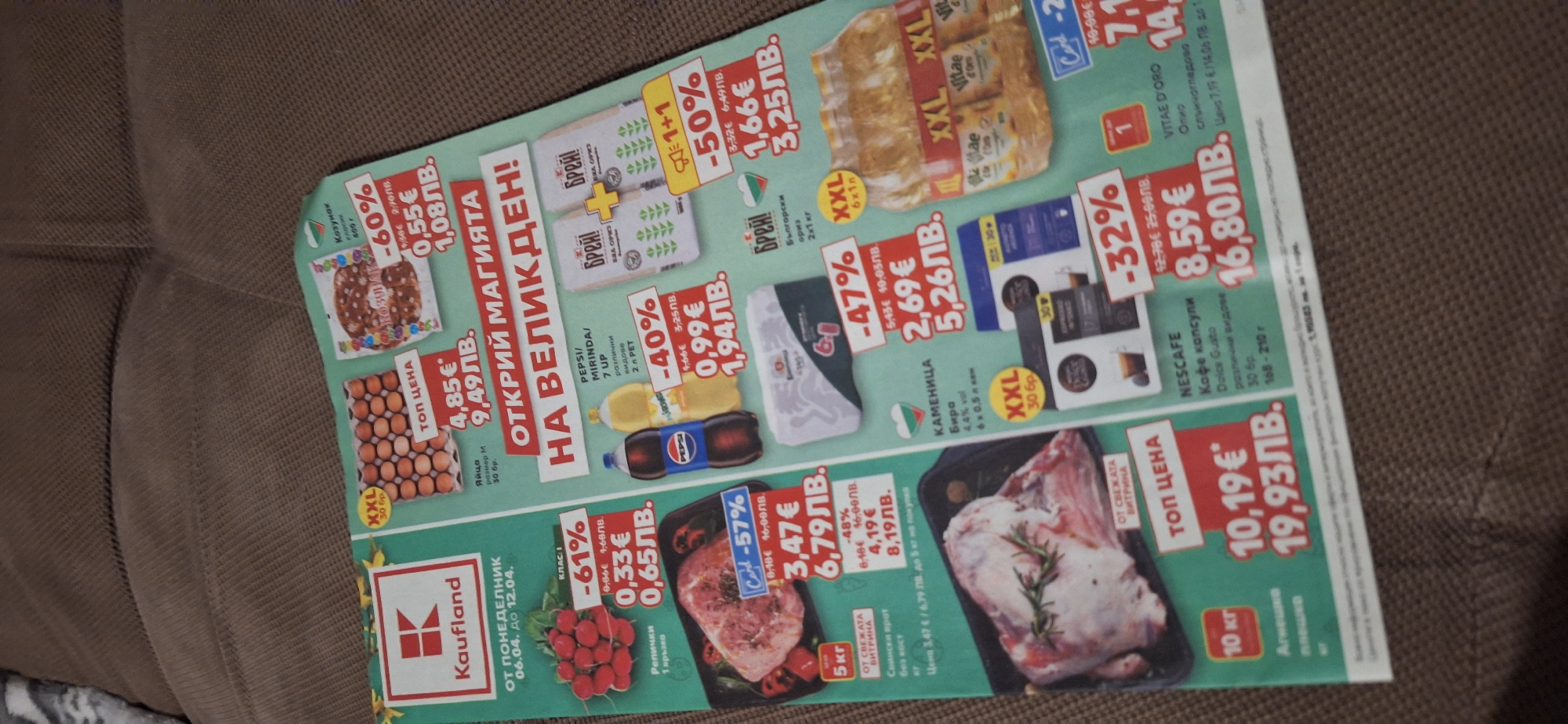 The image shows a promotional flyer, presumably from a Kaufland supermarket in Blagoevgrad, Bulgaria. It features a variety of food items on sale, including radishes, pork, eggs, sweet bread, rice, drinks, coffee, olive oil, and lamb. The flyer advertises discounts on these items, such as "61% off" for radishes, "57% off" for pork, and "32% off" for coffee capsules. Prices are listed in both Euros (€) and Bulgarian Leva (ЛВ). The overall impression is a promotional advertisement targeting customers during the Easter holiday period, highlighted by the text "ОТКРИЙ МАГИЯТА НА ВЕЛИКДЕН!", meaning "Discover the Magic of Easter!".