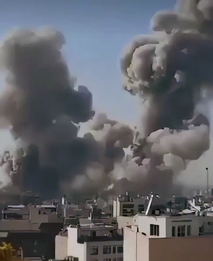 Large smoke clouds rise over city buildings, Tehran. Travel advocacy.