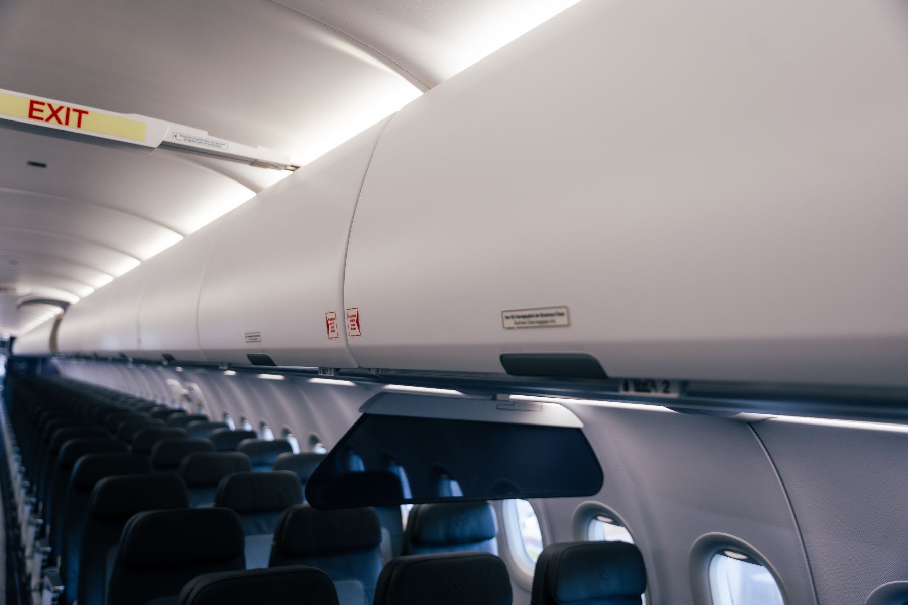 Leere Flugzeugkabine mit Gepäckfächern und Sitzen, welche die eingeschränkten Stauraumoptionen der neuen Tarife verdeutlicht.