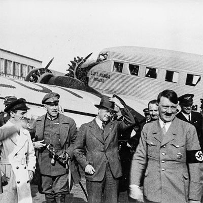 Adolf Hitler und andere Mitglieder der nationalsozialistischen Partei vor einem Lufthansa-Flugzeug.