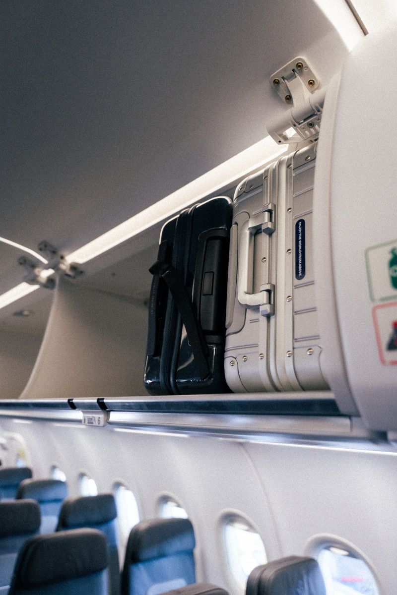 Zwei Koffer im Gepäckfach eines Flugzeugs, passend zum Artikel über die gebührenpflichtige Handgepäckregelung in Economy Basic Tarifen.