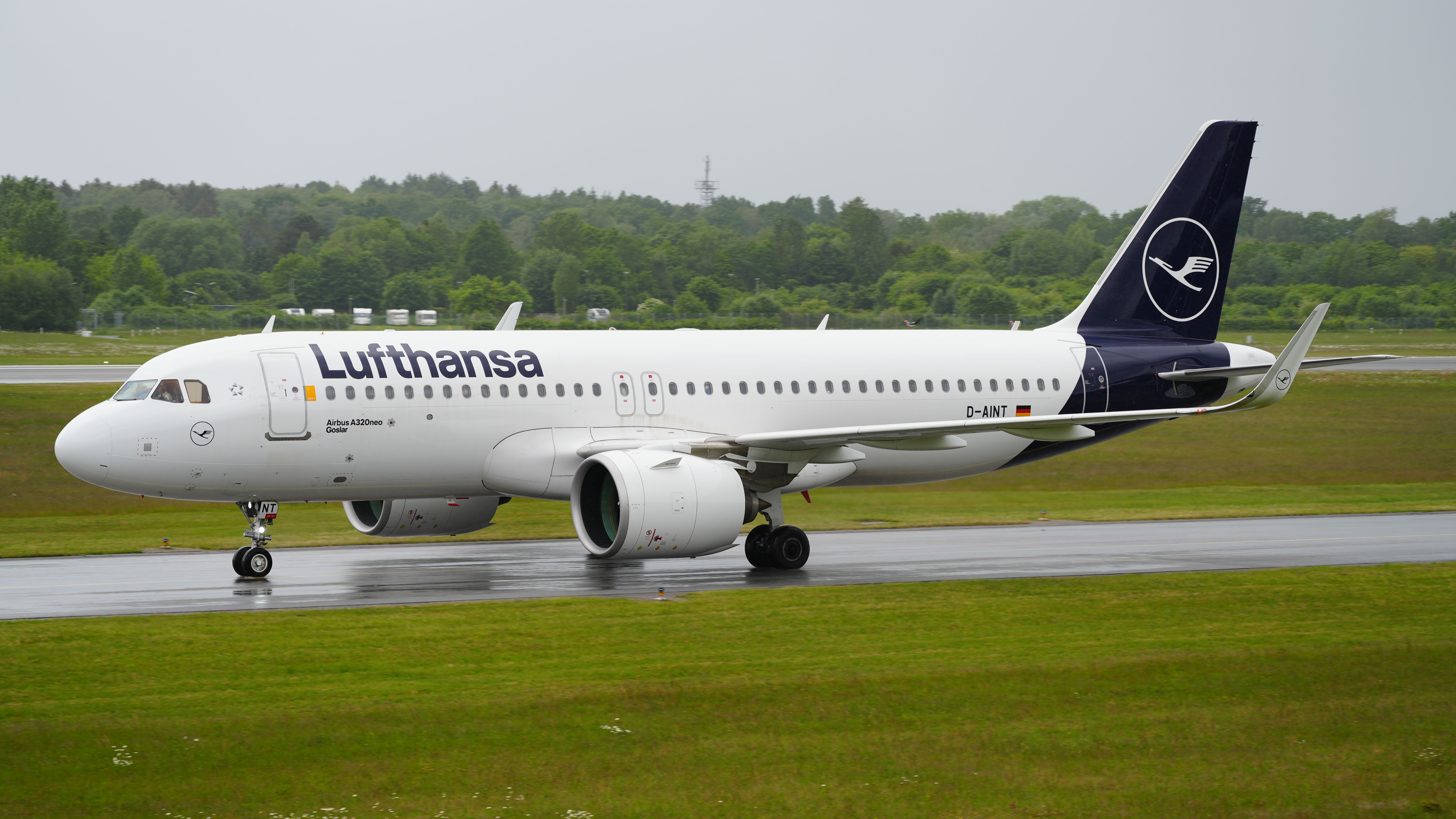 Lufthansa A320neo rollt auf regnerischer Landebahn. Die Sicht ist schlecht.