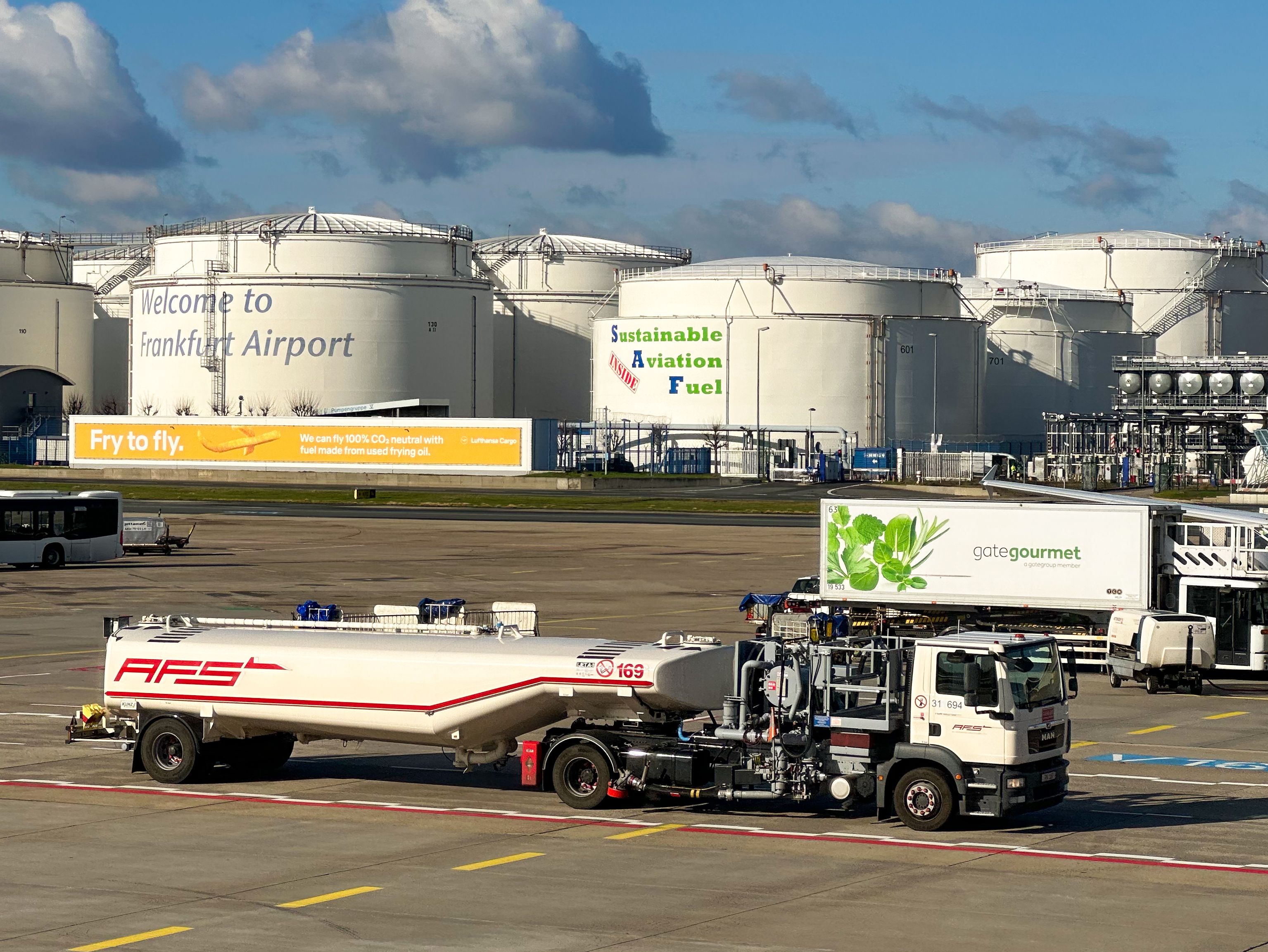 Tankwagen am Flughafen Frankfurt mit Werbung für nachhaltigen Flugkraftstoff auf nahegelegenen Lagertanks.