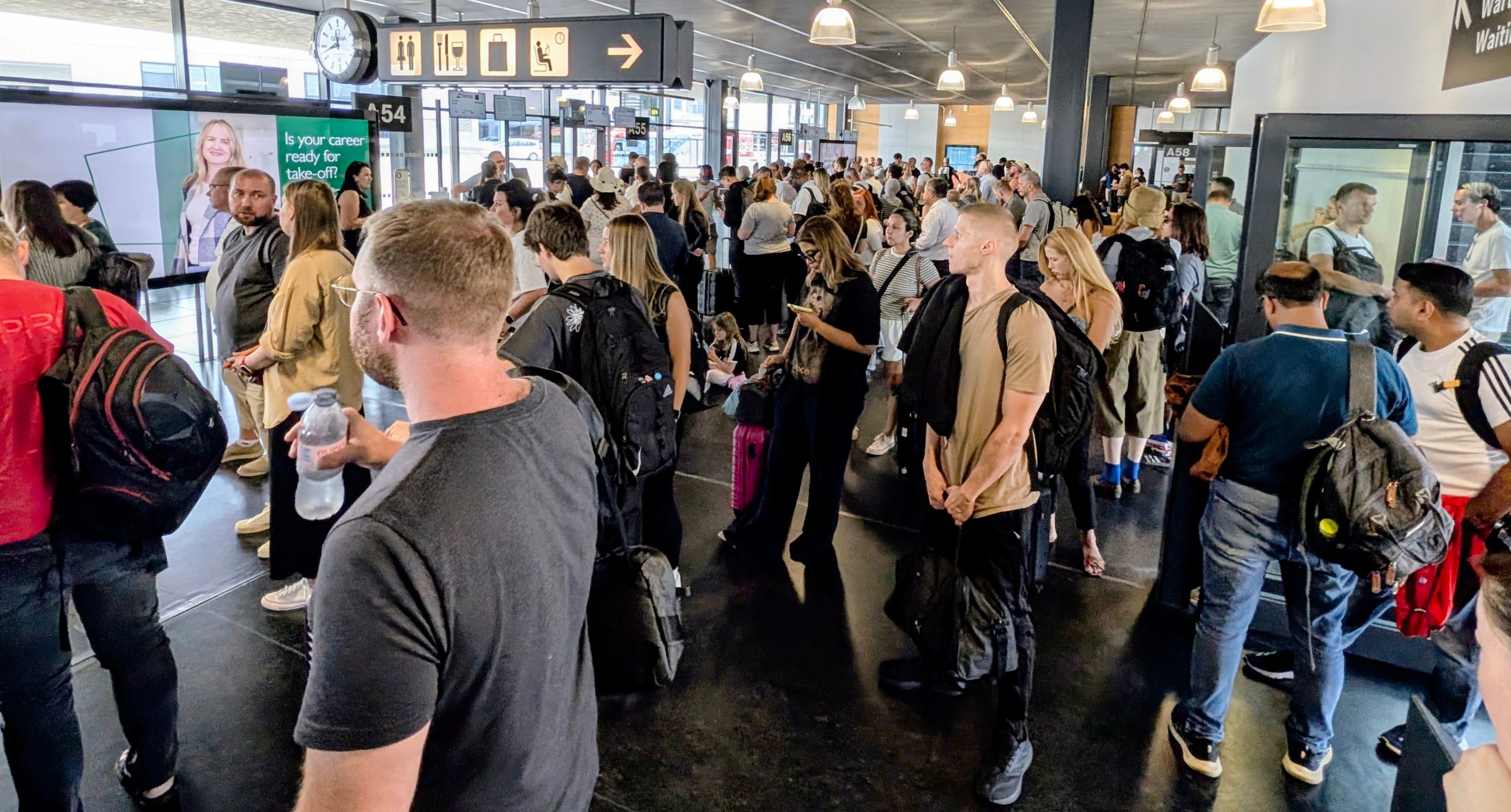 Überfüllter Abflugbereich am Flughafen: Dicht gedrängte Passagiere warten, was die geschäftigen Reisebedingungen zeigt.