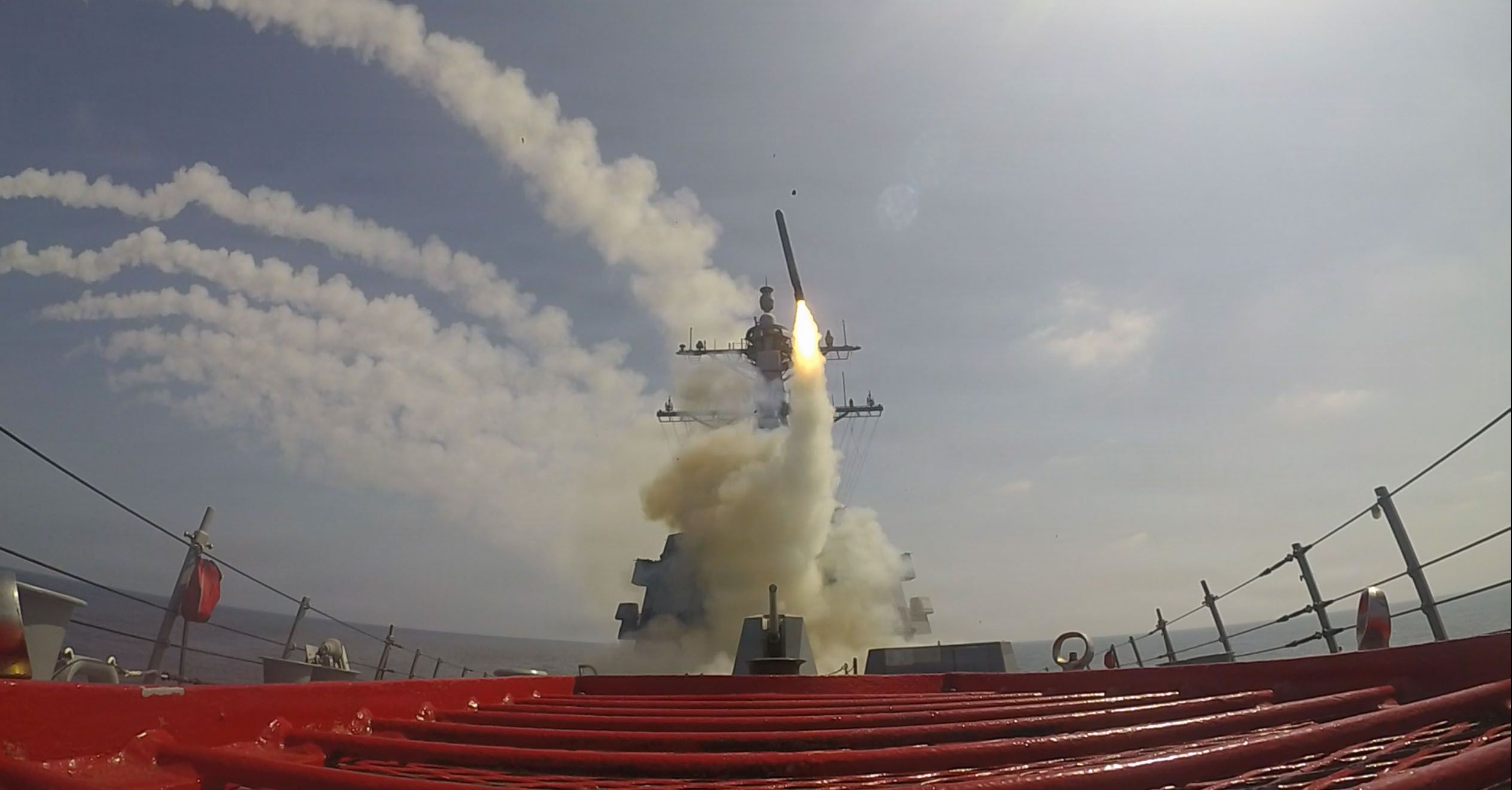 Missile launch from a warship, smoke and fire visible.