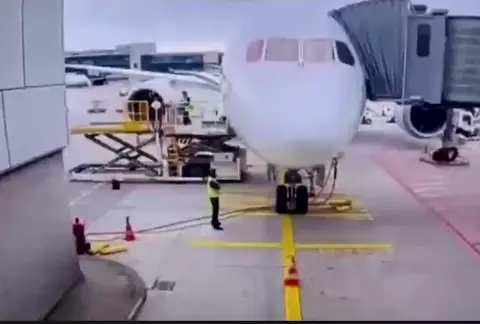 Video, das den Zusammenbruch des Bugfahrwerks einer Lufthansa 787 zeigt, umringt von Bodenpersonal.