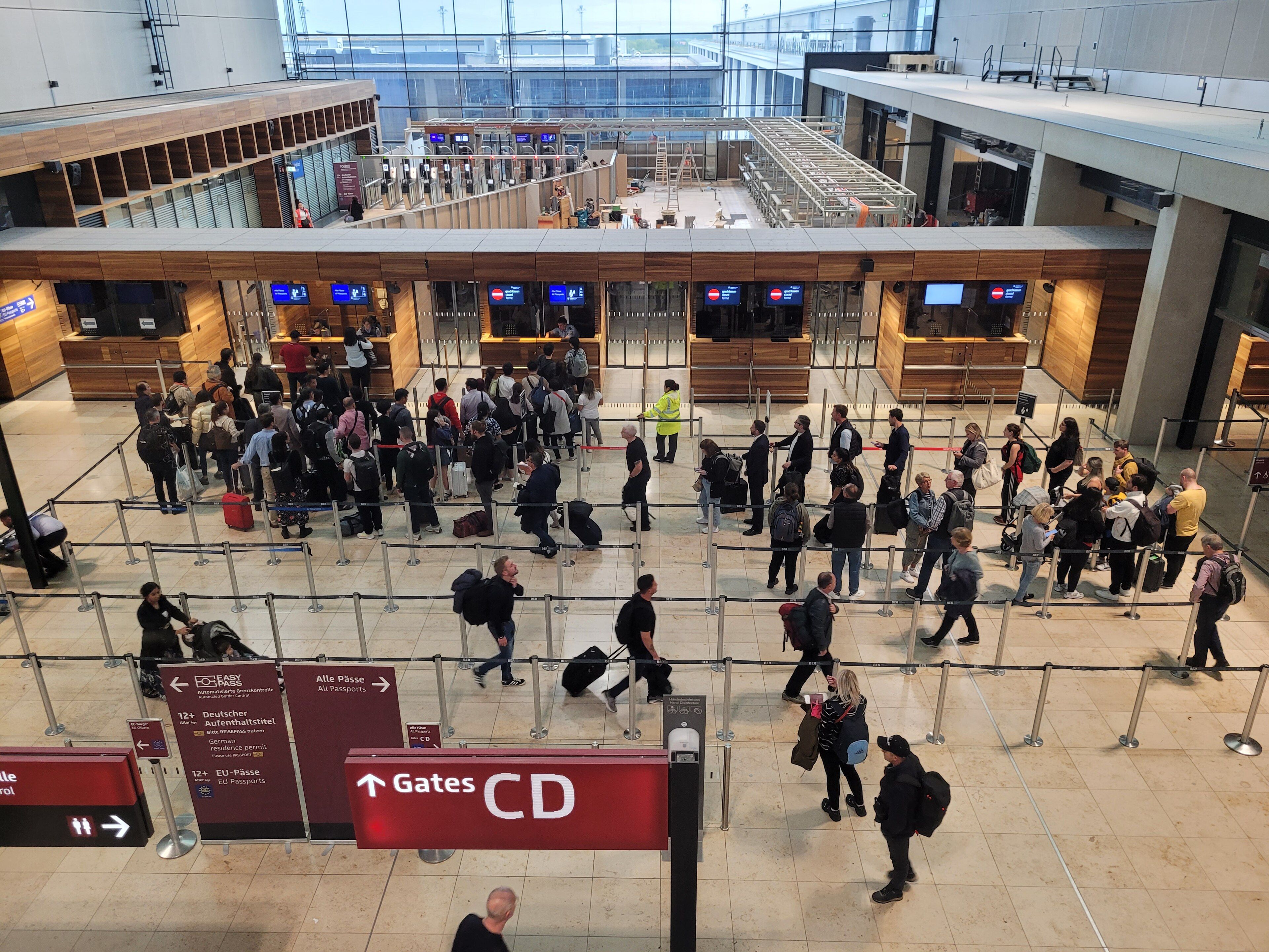 Volle Passkontrolle am BER Flughafen; Reisende warten in der Schlange.