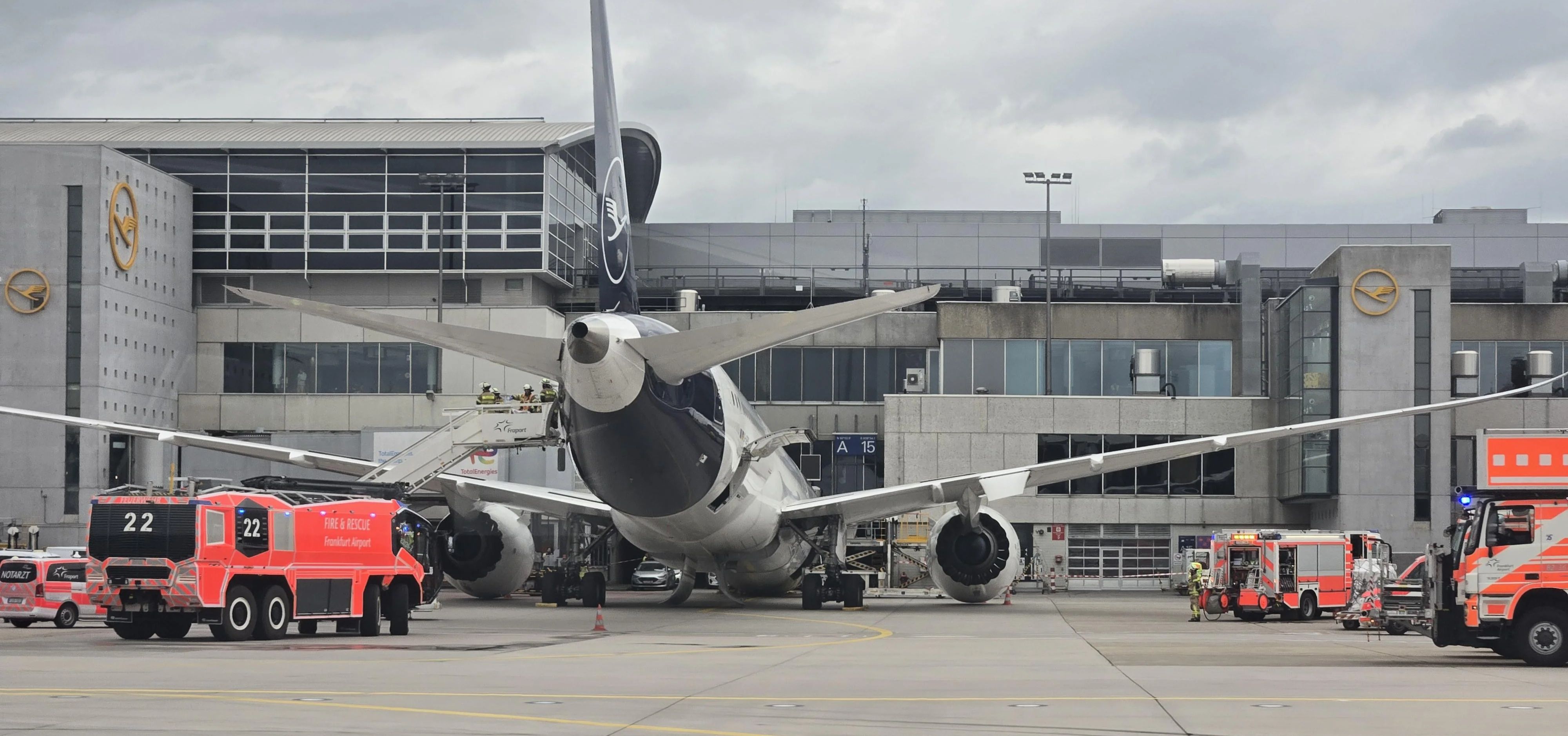 Lufthansa Boeing 787 Dreamliner mit eingestürztem Bugfahrwerk am Frankfurter Flughafen. Einsatzfahrzeuge umringen das beschädigte Flugzeug.