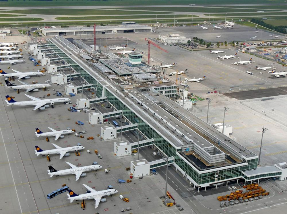 Luftaufnahme des Münchner Flughafens mit Lufthansa-Flugzeugen und Terminalbau.