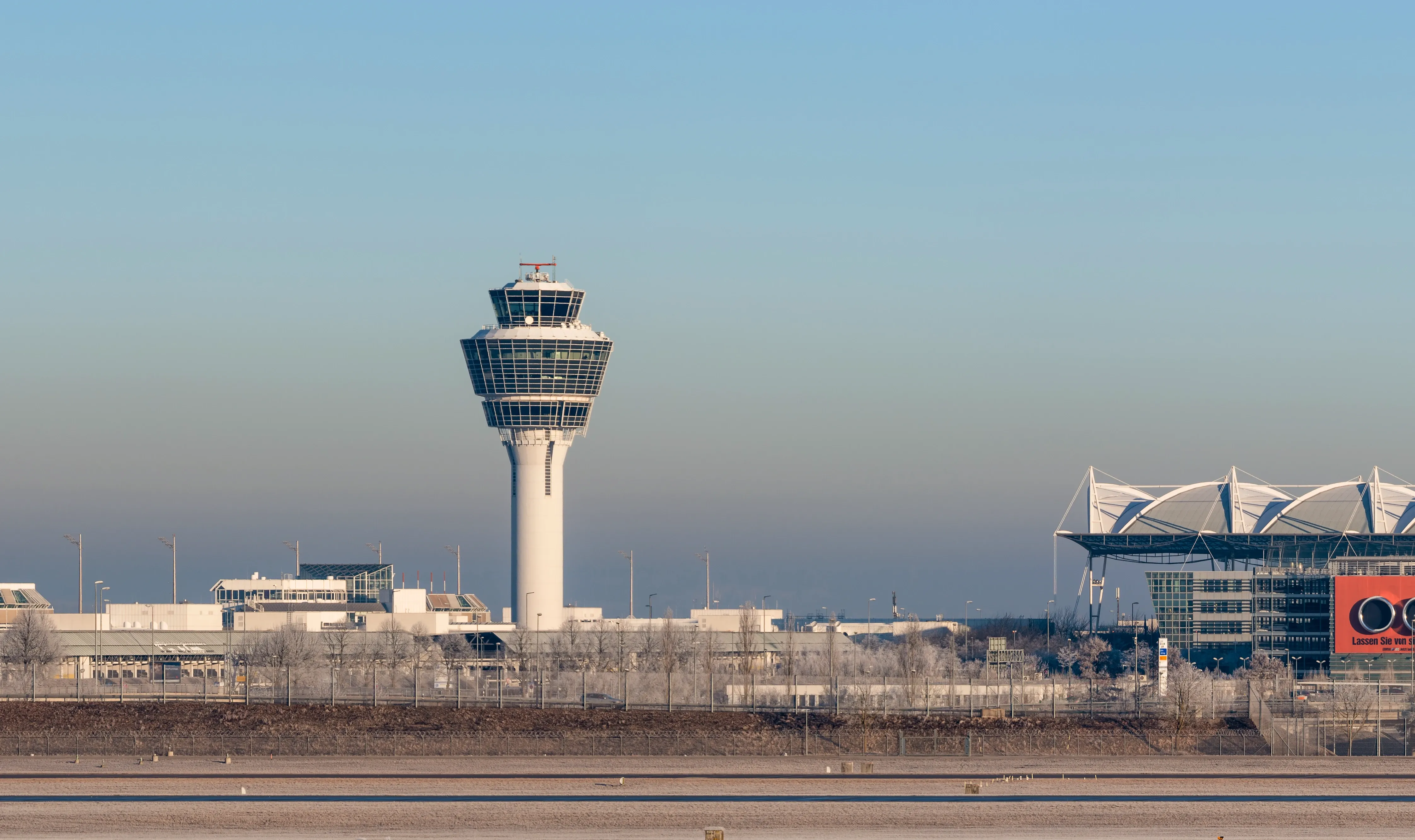 Der Kontrollturm und das Terminal des Münchner Flughafens an einem klaren, kalten Tag. Frostiger Boden.