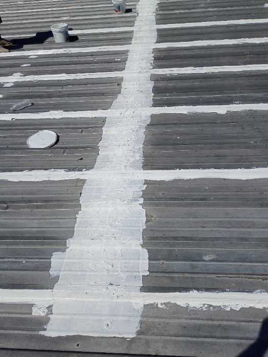 Priming rust spots on metal roof to get ready for silicone in Madison, MS