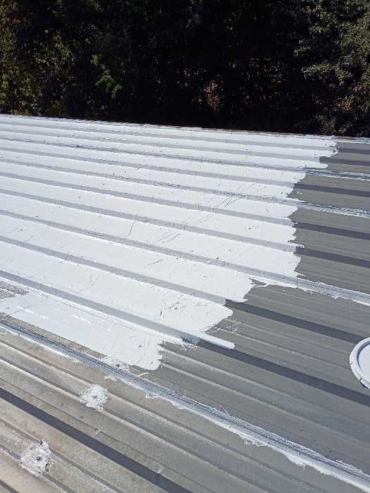 Rolling silicone on a metal roof to seal it in Madison, MS