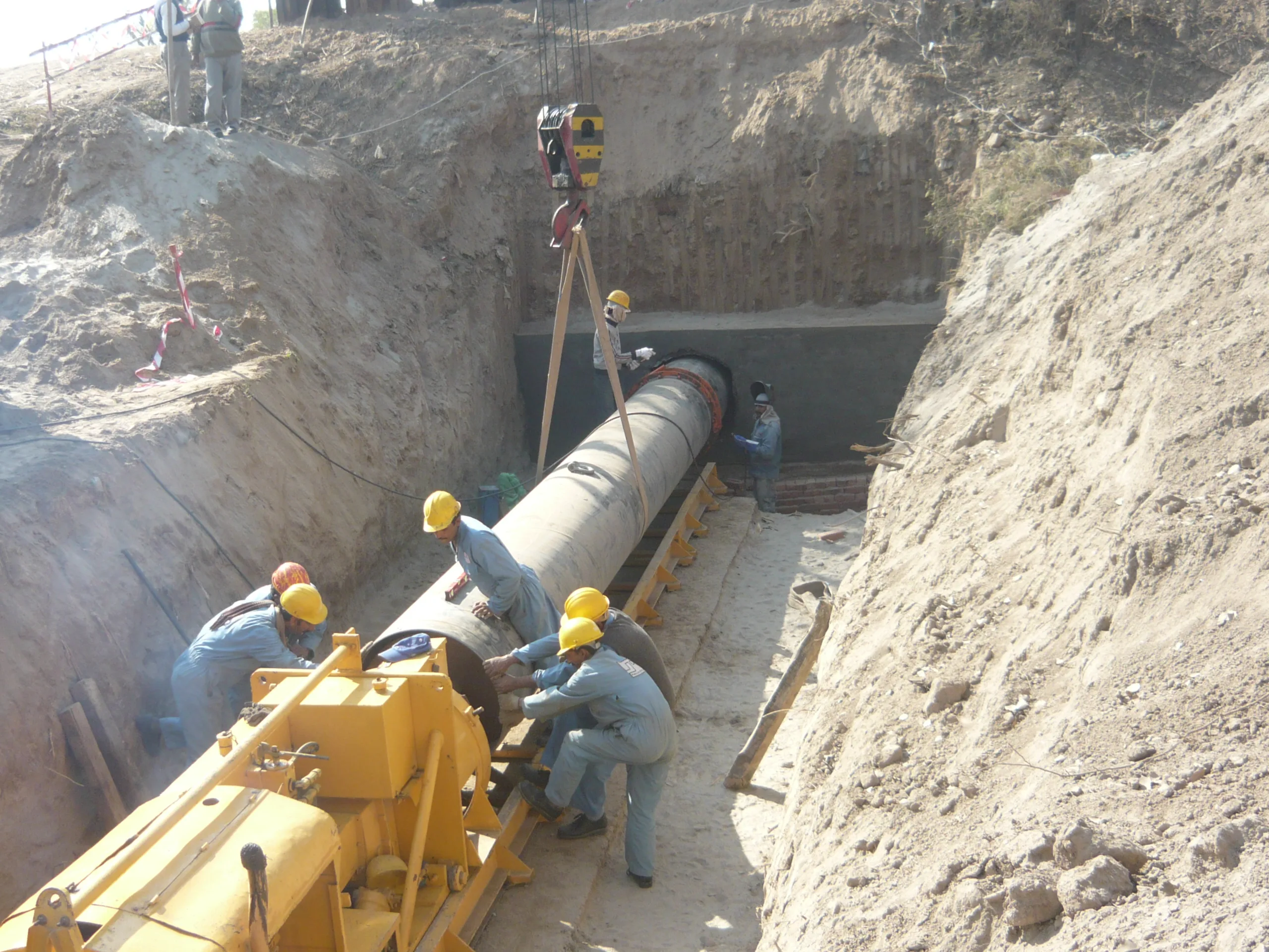 Hydraulic pipe-jacking rig pushing a steel casing pipe into a bore beneath an embankment