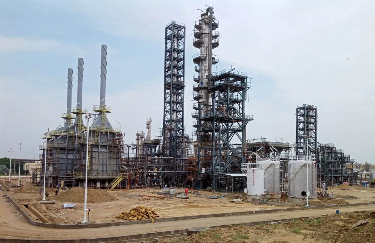 Refinery under construction: distillation columns, structural steel framing, process heater and storage tanks