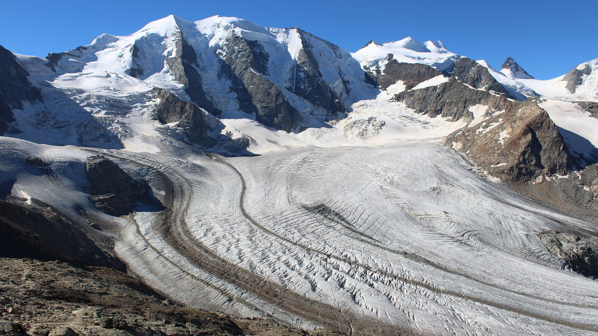 The Pers glacier below Piz Palü, seen from the Diavolezza, with snow-covered peaks under a blue sky