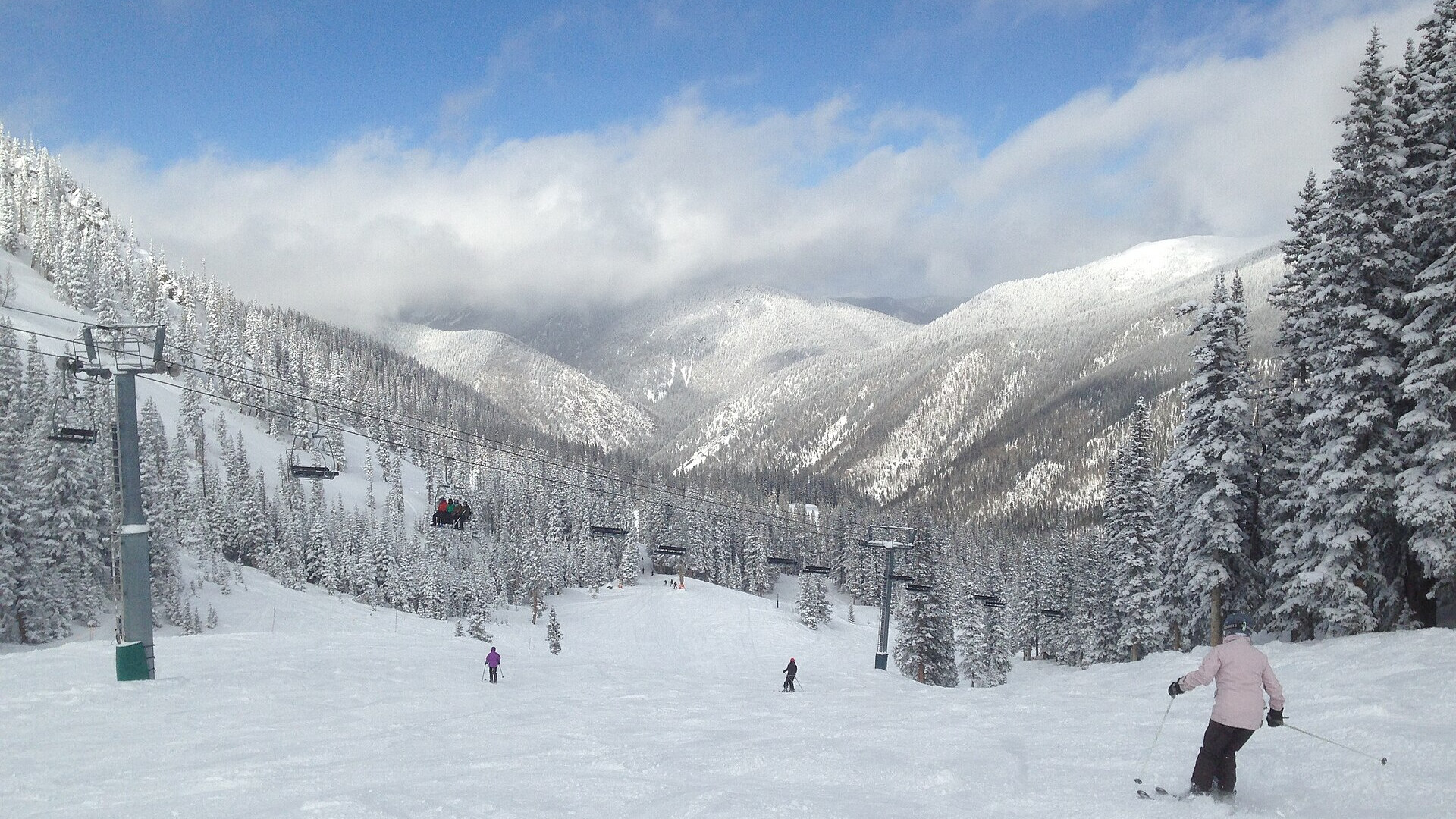 Des skieurs sur une piste enneigée sous un télésiège à Taos Ski Valley, au Nouveau-Mexique
