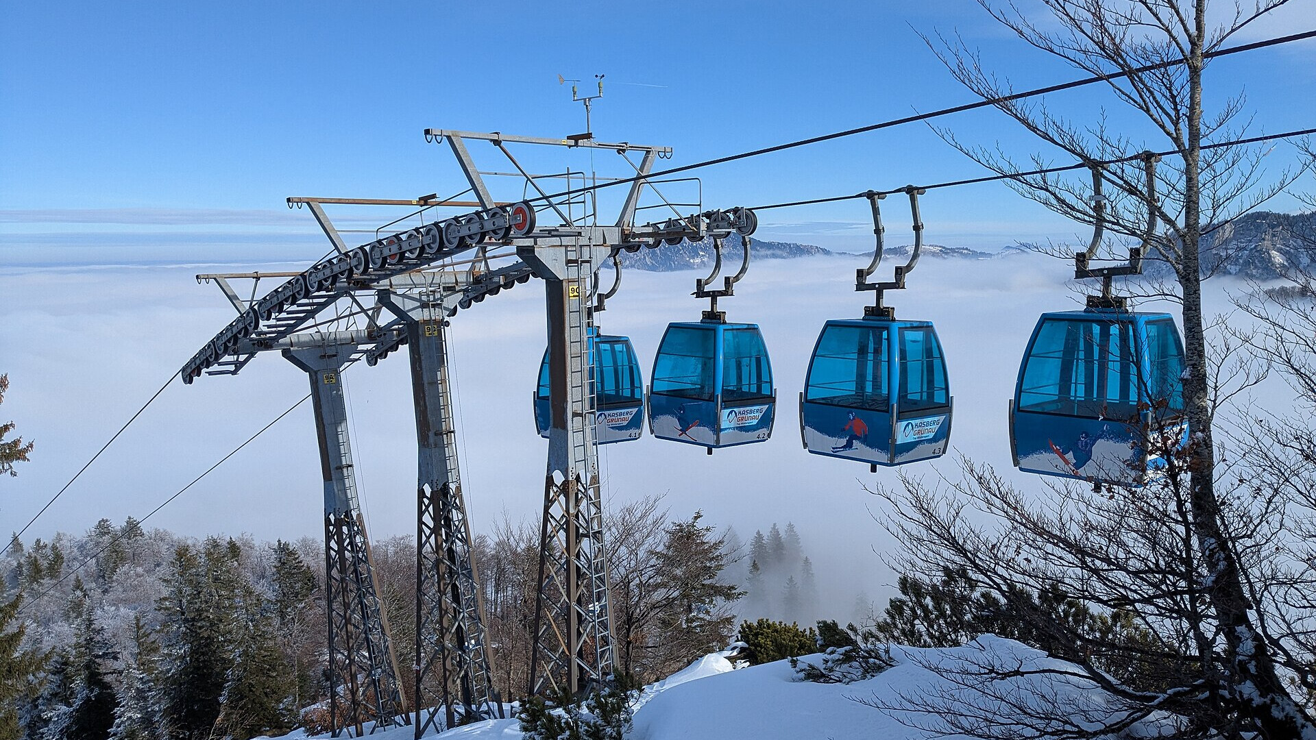 Blaue Kabinen der Gruppenumlaufbahn am Kasberg über einem Nebelmeer im Winter