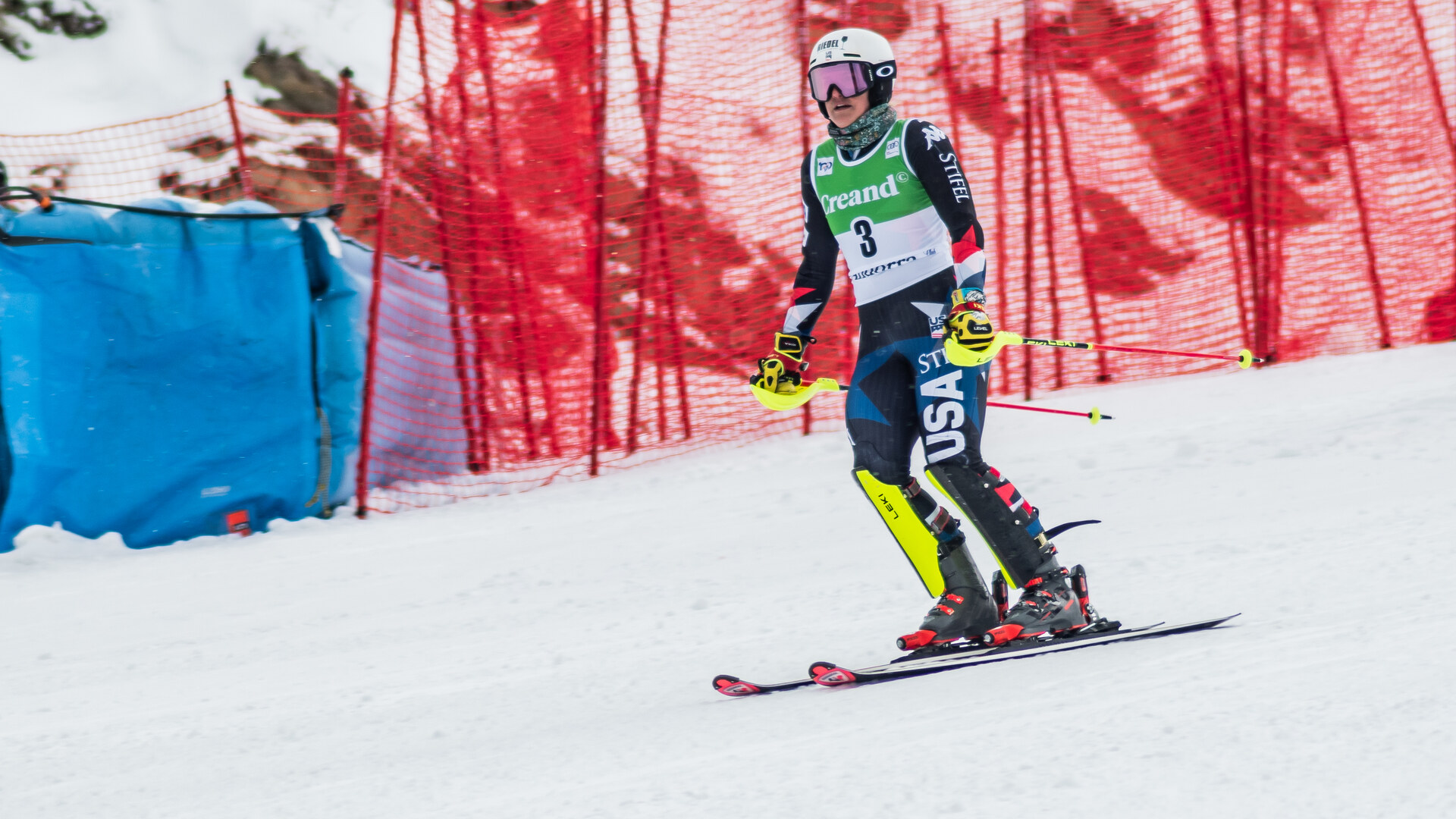 Paula Moltzan on skis in a race bib between red slalom gates, looking down the course