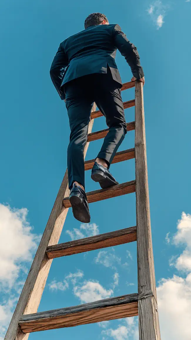 Man climbing up a wooden ladder against a blue sky