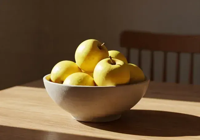 Sunlit Bowl of Yellow Apples