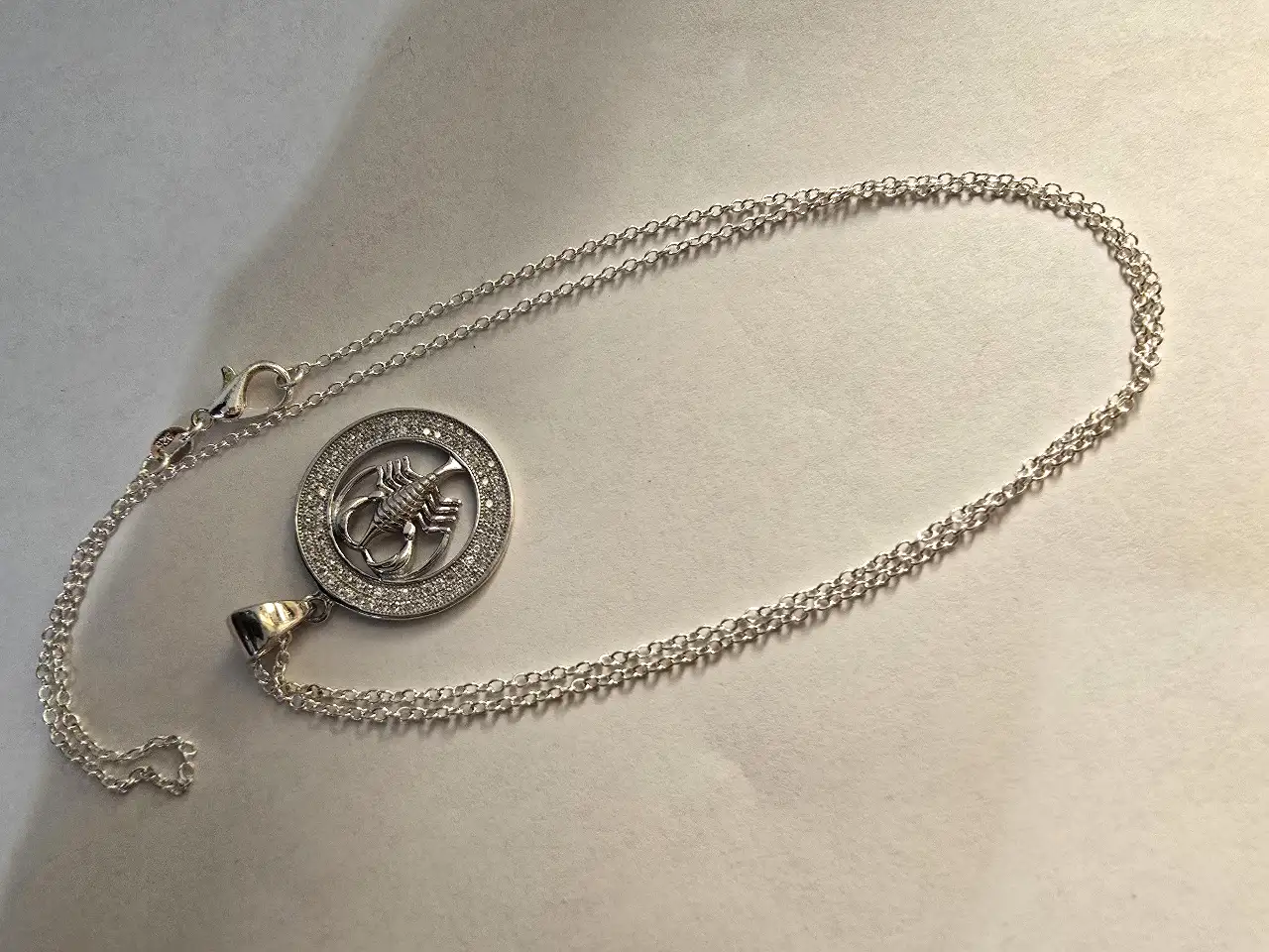 שרשרת כסף 925 עם תליון עגול המעוטר באבני זירקוניה קטנות סביבו ובמרכז דמות של עקרב ..תליון מזל עקרב