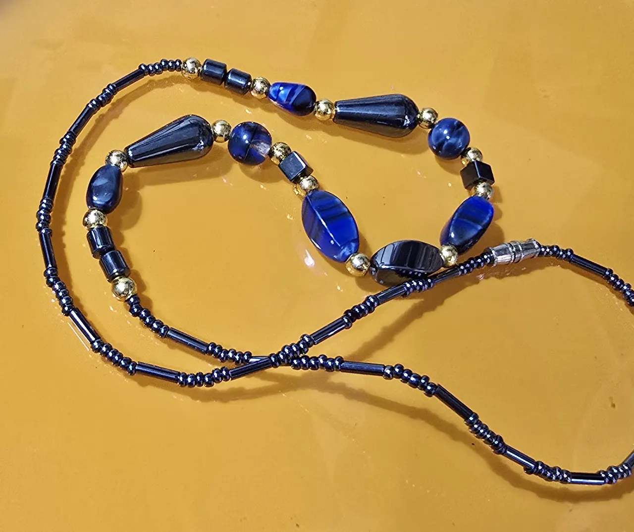 שרשרת חרוזי אבן המטיס בגוונים כחול ושחור וחרוזי זהב קטנים